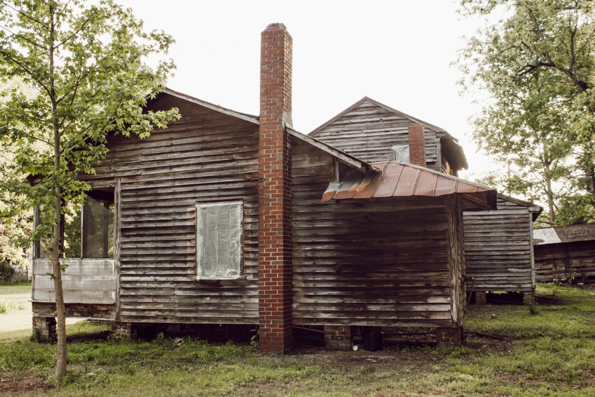 1800's NC farmhouse with weathered wood siding and red brick chimney