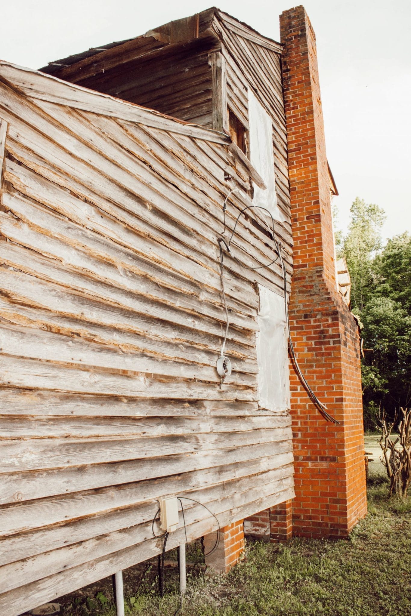 1800's NC farmhouse with weathered wood siding and red brick chimney