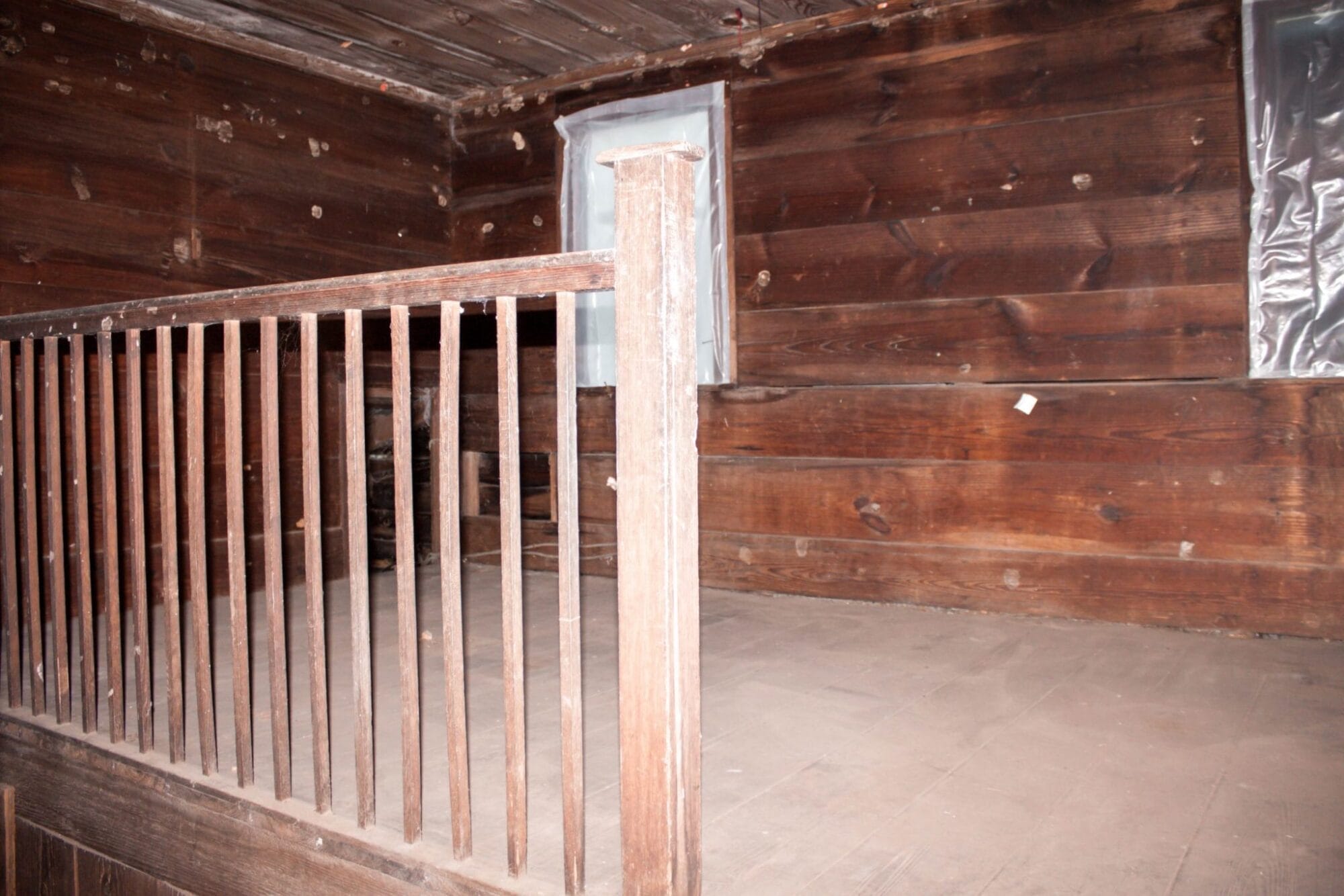 stair railing in 1800's NC farmhouse upstairs bedroom with original shiplap on walls and wood floors
