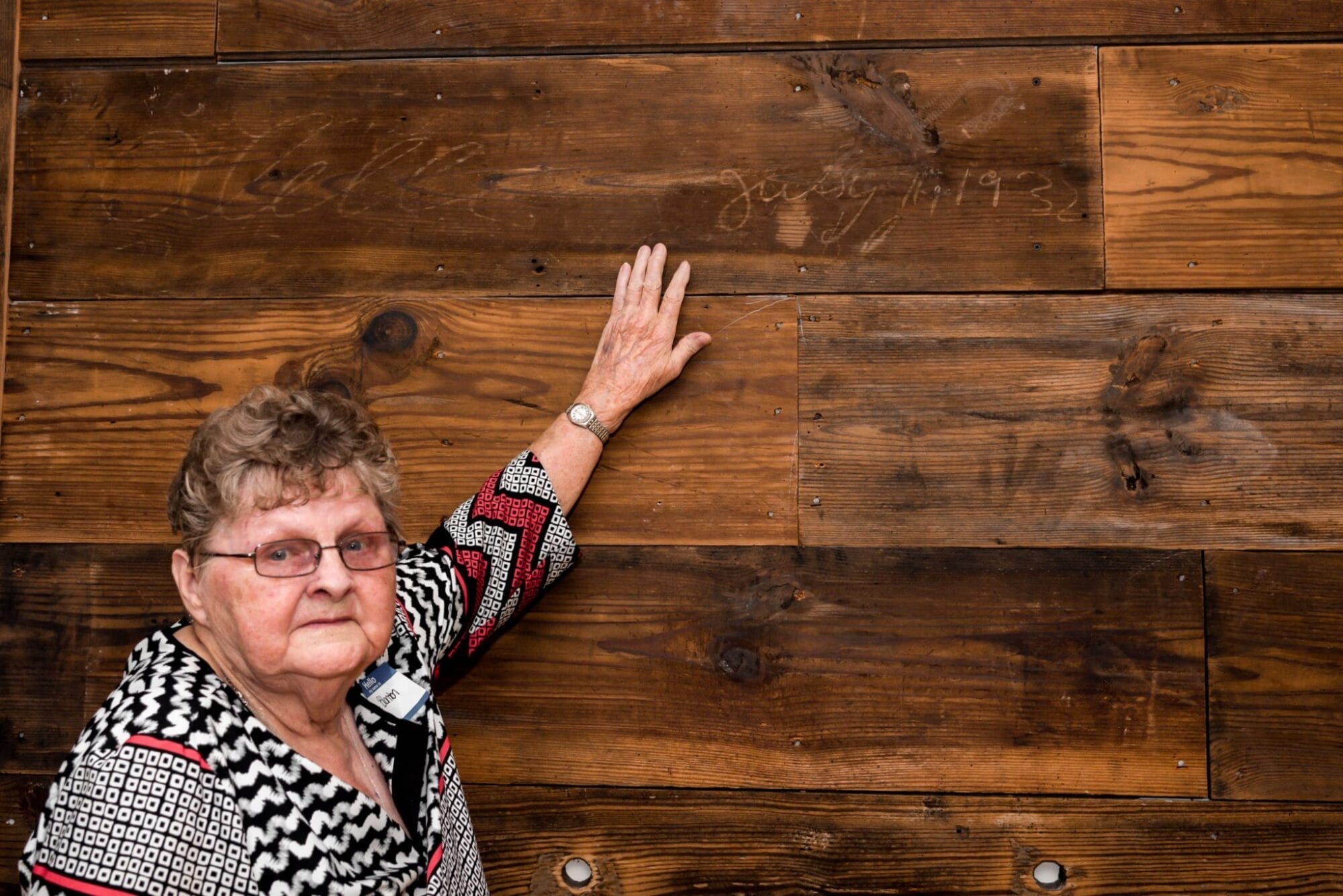 daughter placing hand on father's name on shiplap feature wall