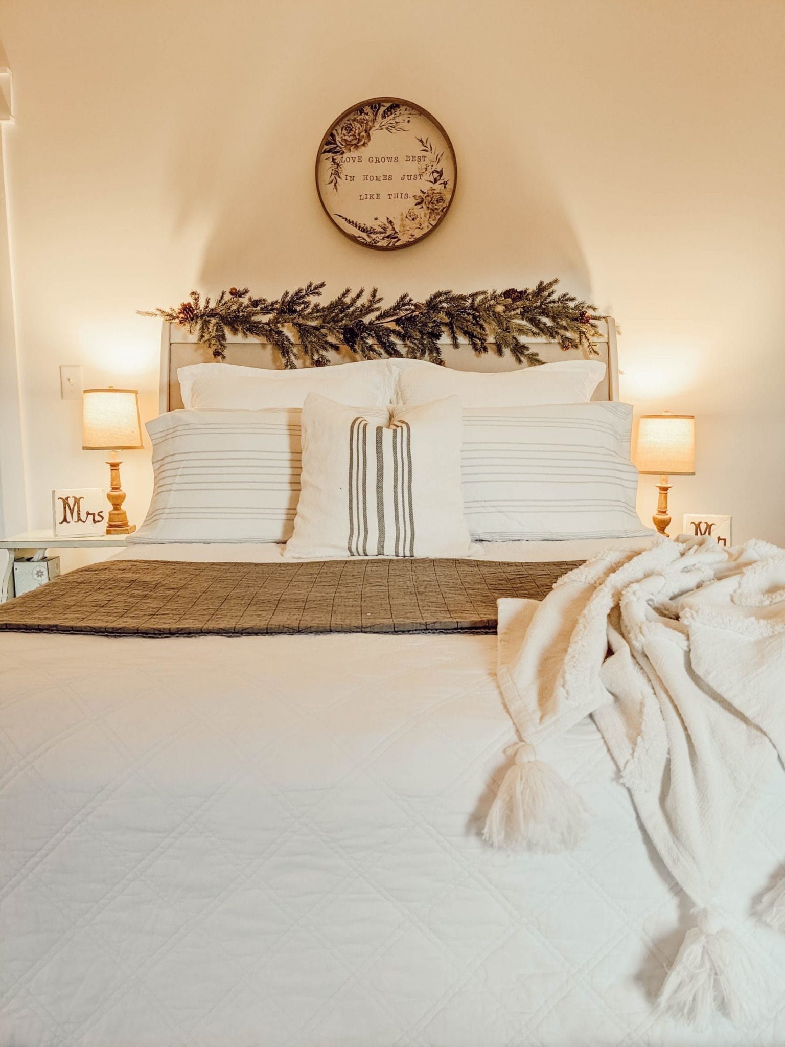 white farmhouse style Christmas bedding and upholstered headboard with garland