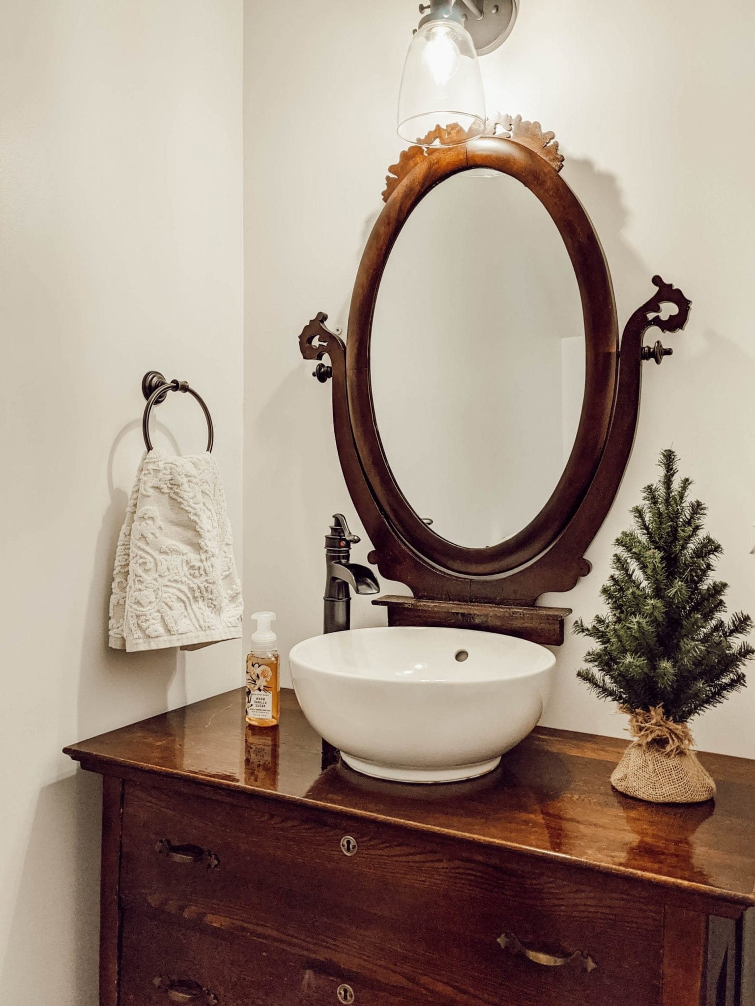 mini burlap wrapped Christmas tree atop dresser style bathroom vanity