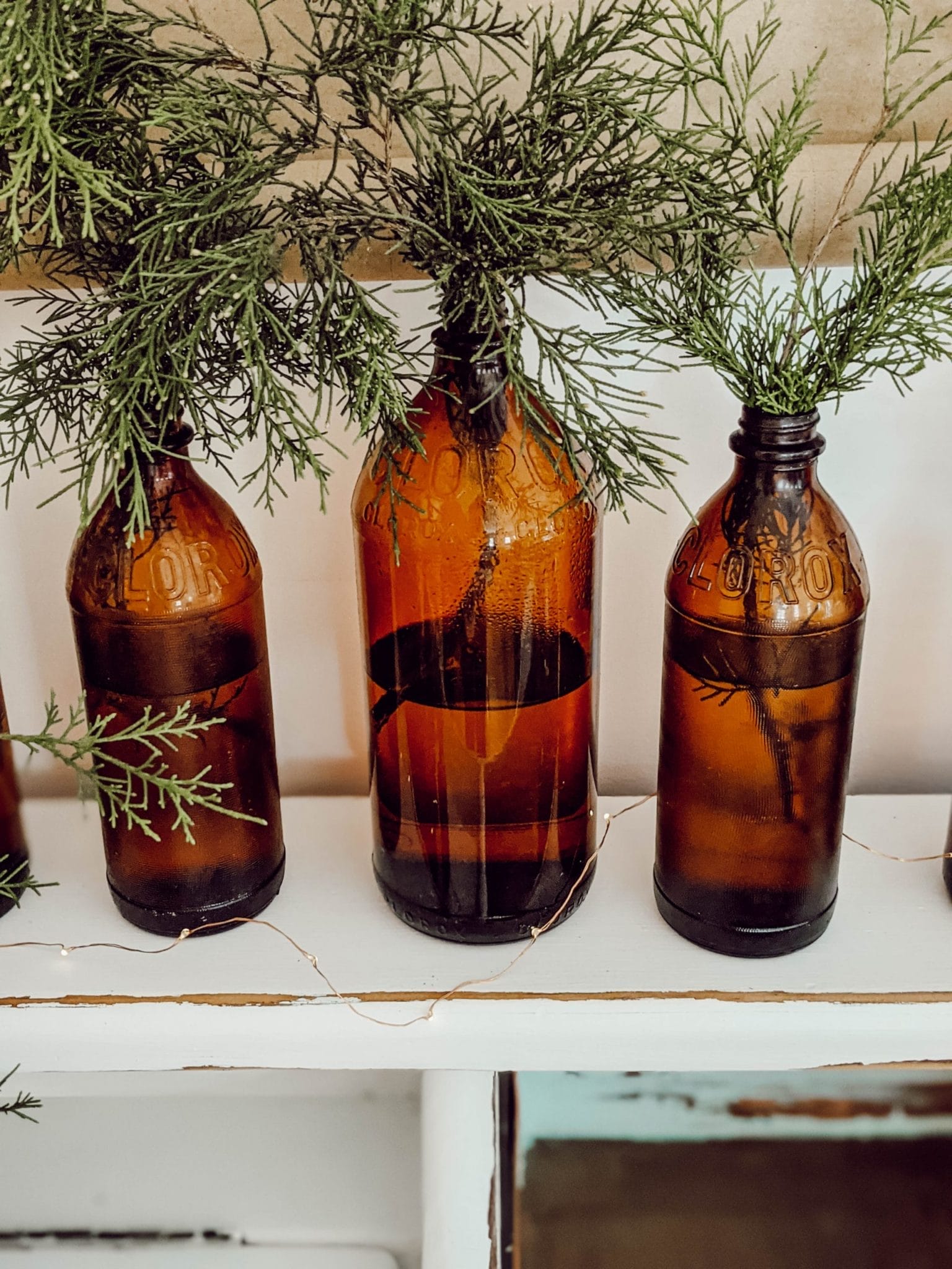 antique brown glass clorox bottles with cedar greenery