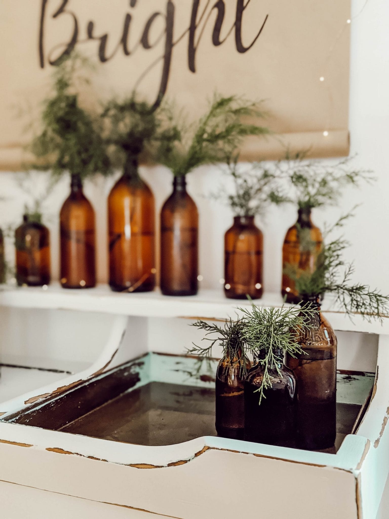 simple holiday decor using brown glass bottles and fresh greenery