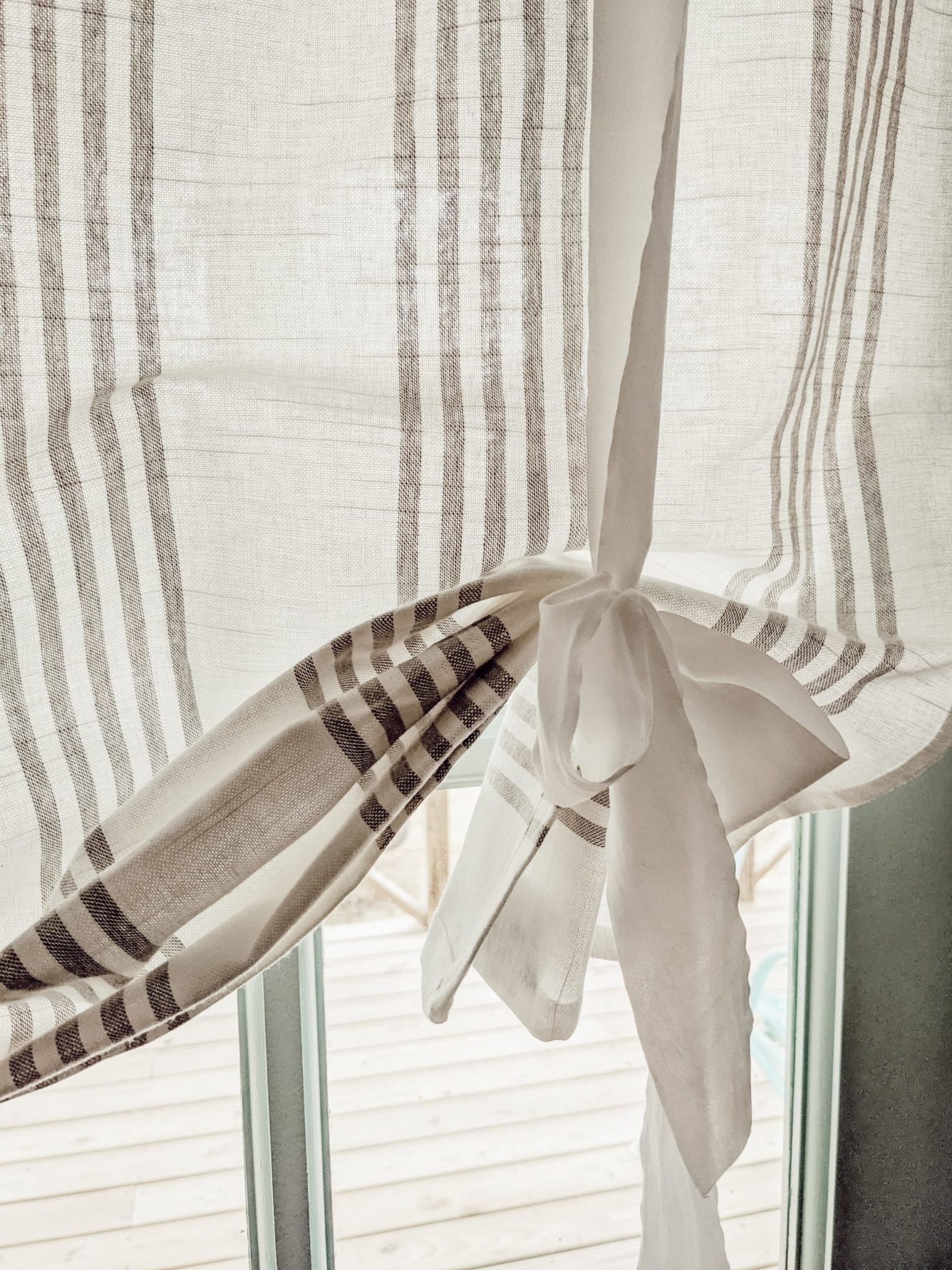 simple white bow on gray and white striped curtain
