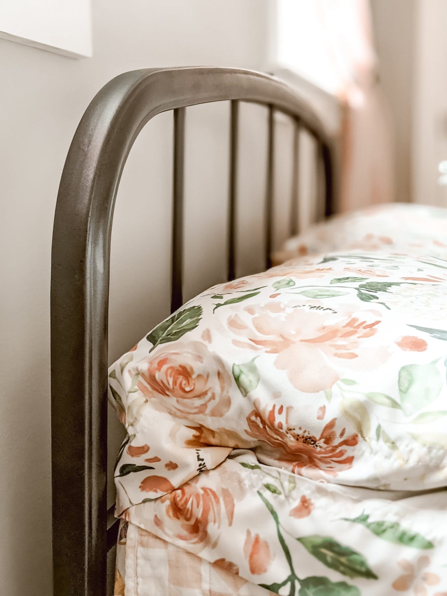vintage metal bed with pink and white bedding and vintage floral pillow cases