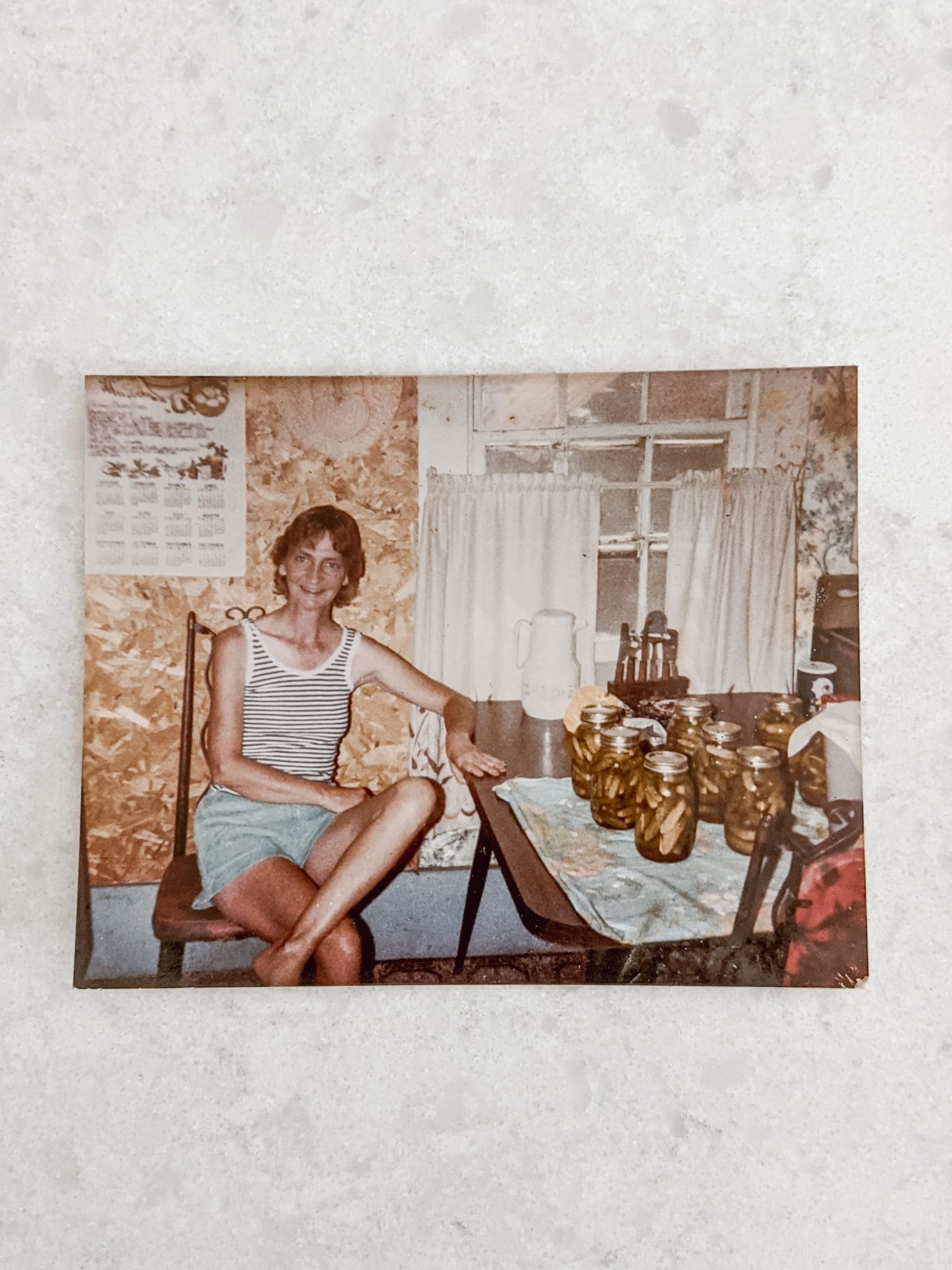 Grandmother smiling proudly with yield of homegrown homemade mason jars full of pickles