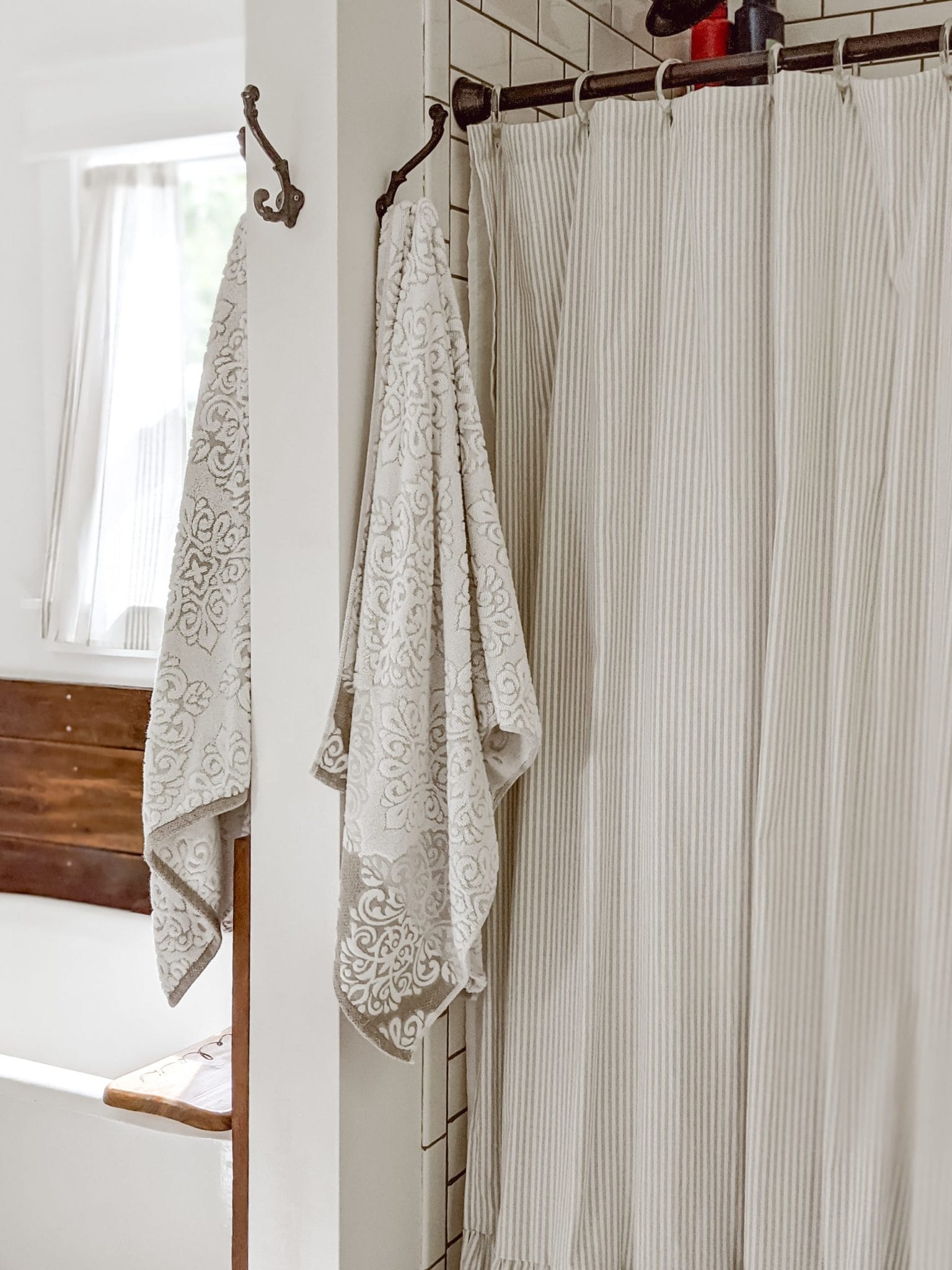 fresh white towels hung on an antique iron hook by the shower