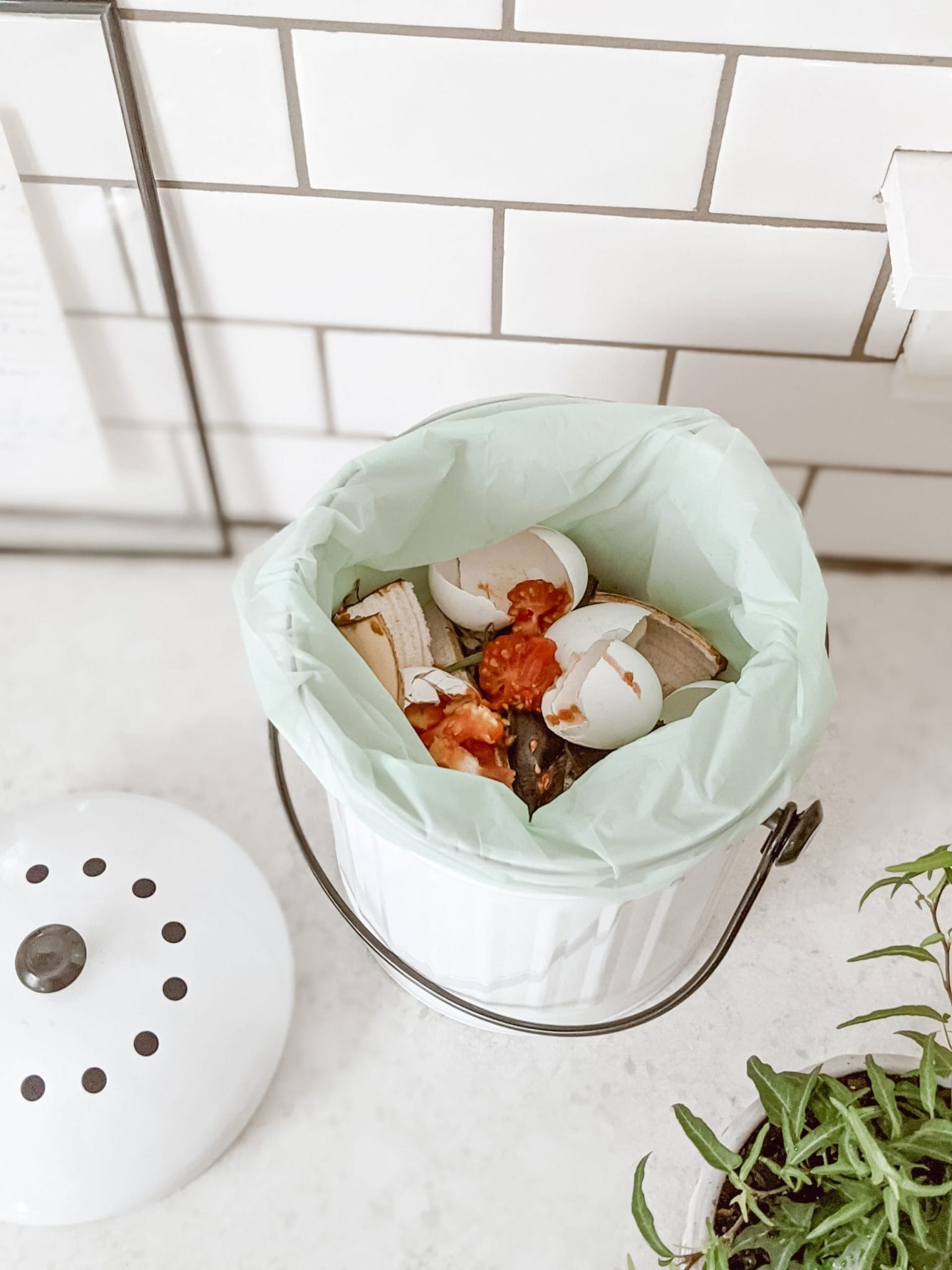 kitchen compost pail with compostable bag and lots of food scraps