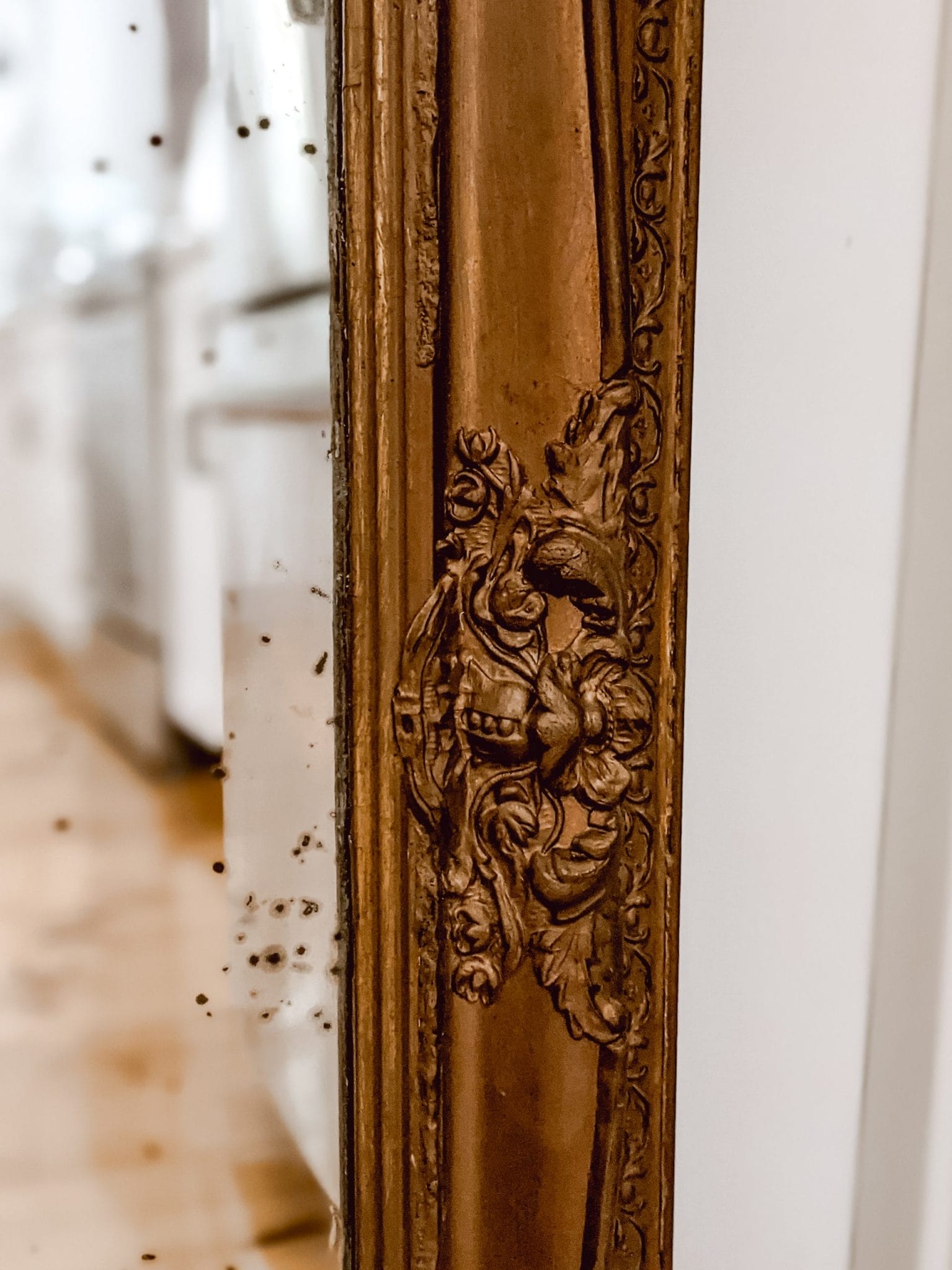 antique gold mirror with intricate frame and black oxidation spots on the glass