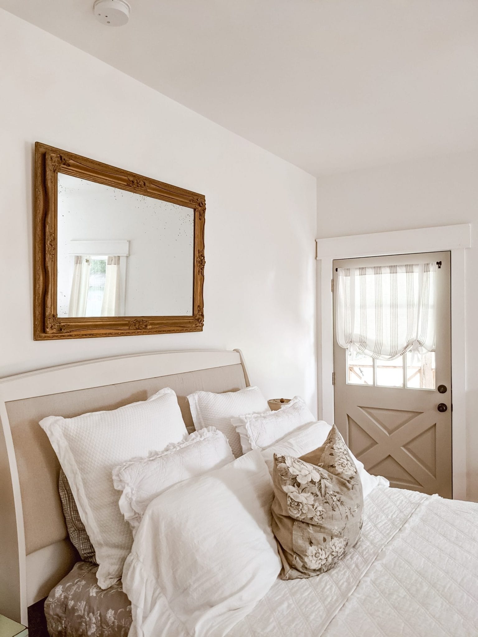 antique gold framed mirror hung above upholstered bed from a recent thrifting trip to The Habitat For Humanity ReStore