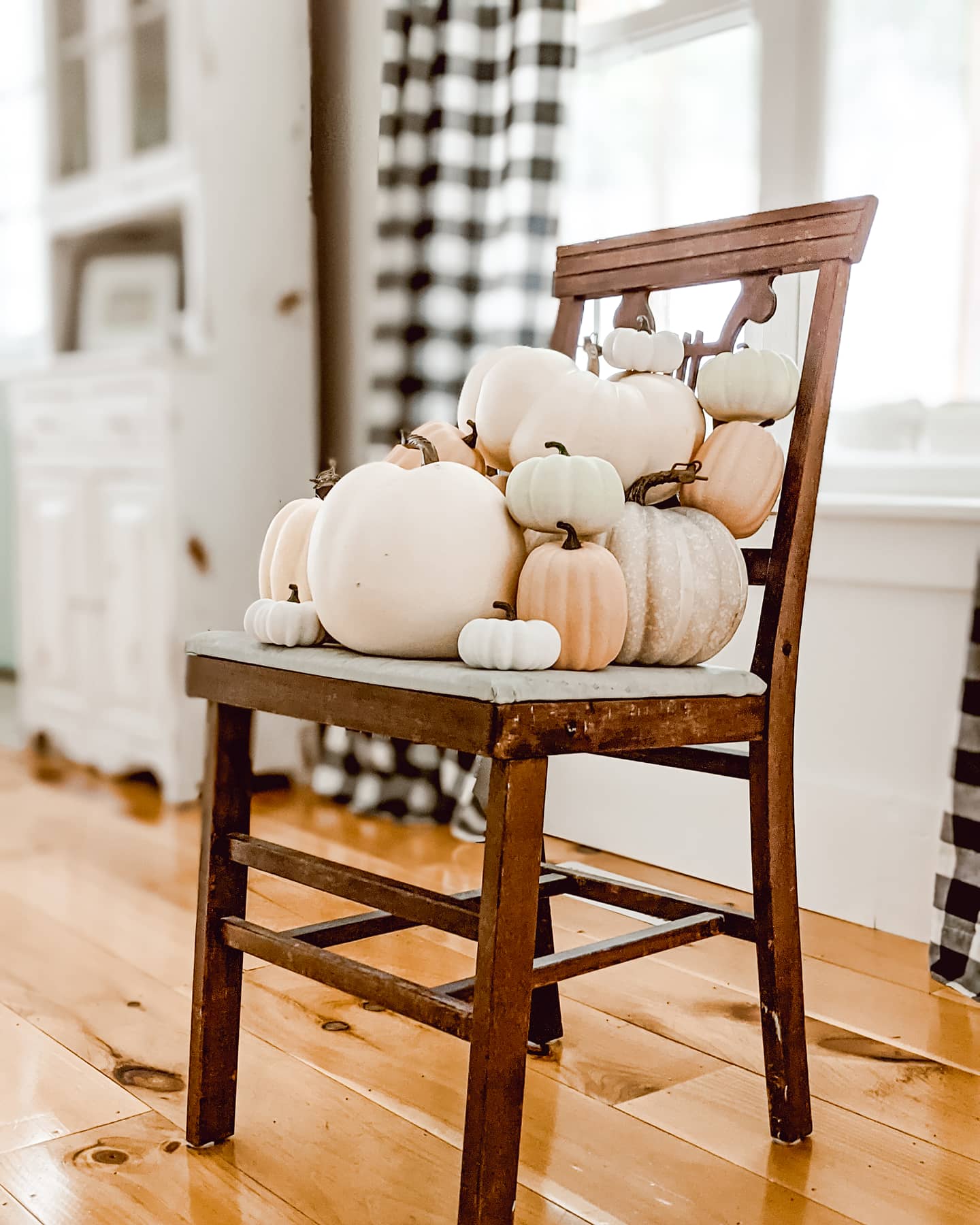 faux pumpkins stacked in a vintage wooden chair