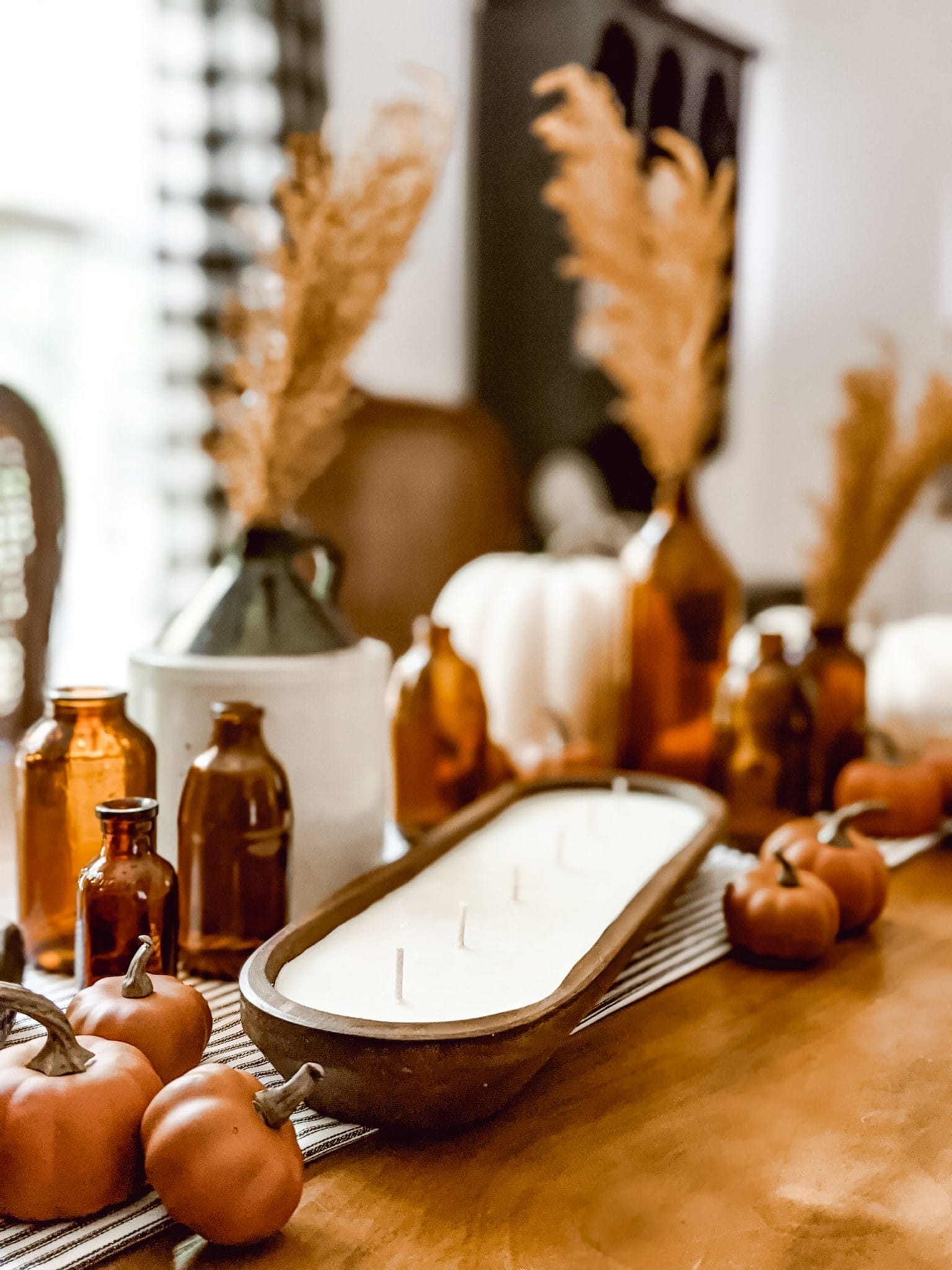 farmhouse tablescape with amber glass, pumpkins, and a dough bowl candle