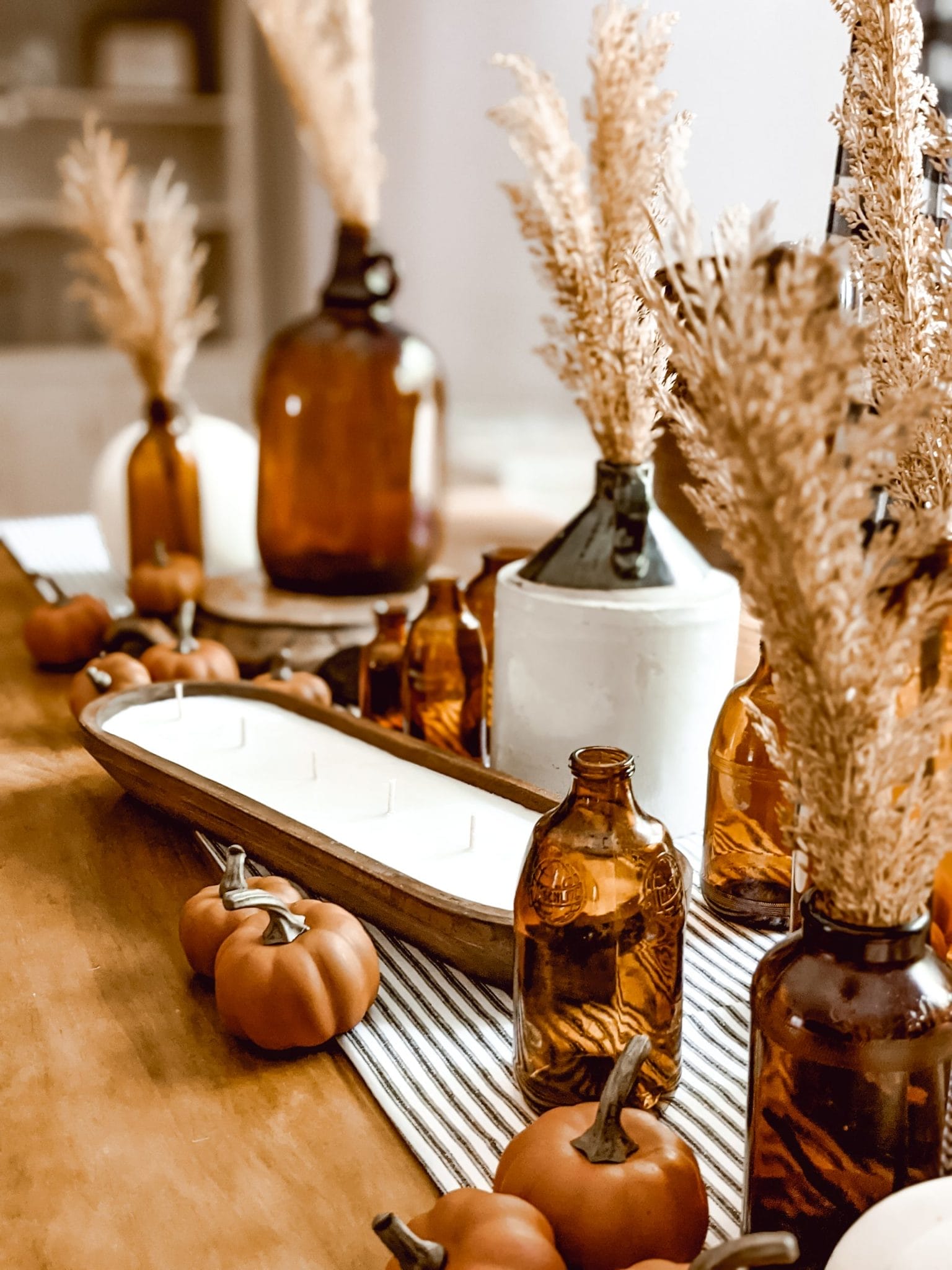 farmhouse tablescape with amber glass, pumpkins, and a dough bowl candle