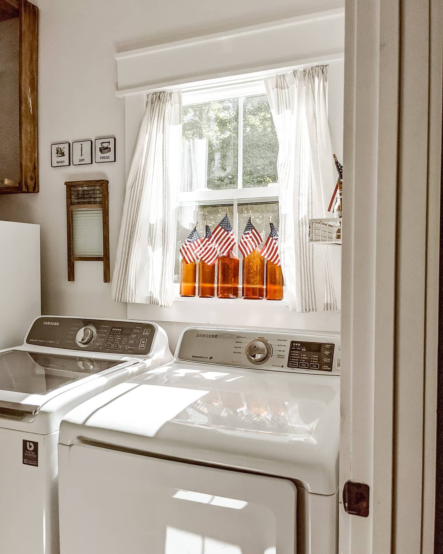 amber glass clorox bottles with vintage American flags sitting on the window sill in a white farmhouse laundry room