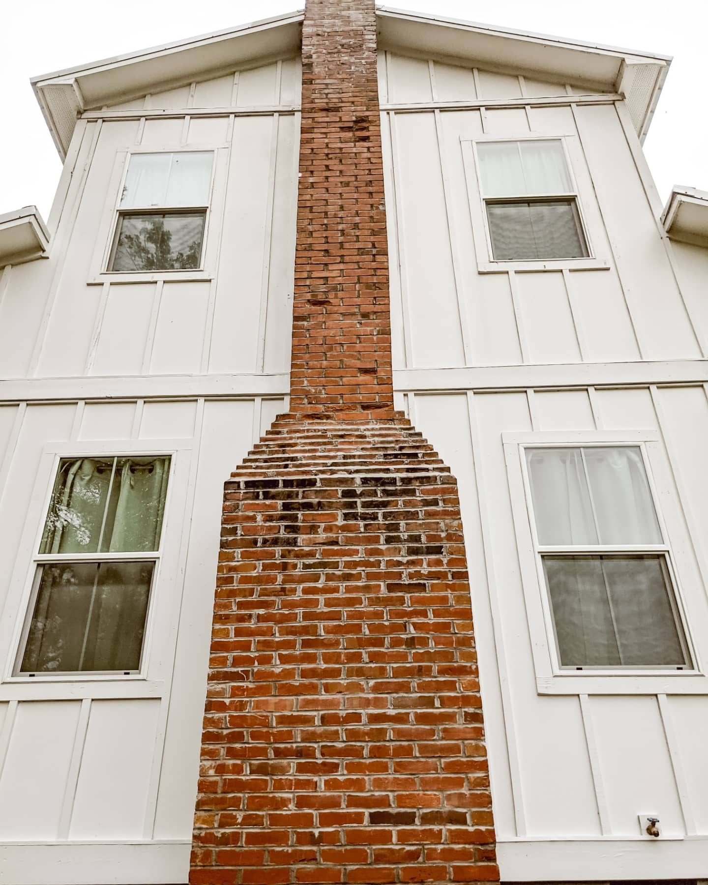 white farmhouse with board and batten siding and brick chimney