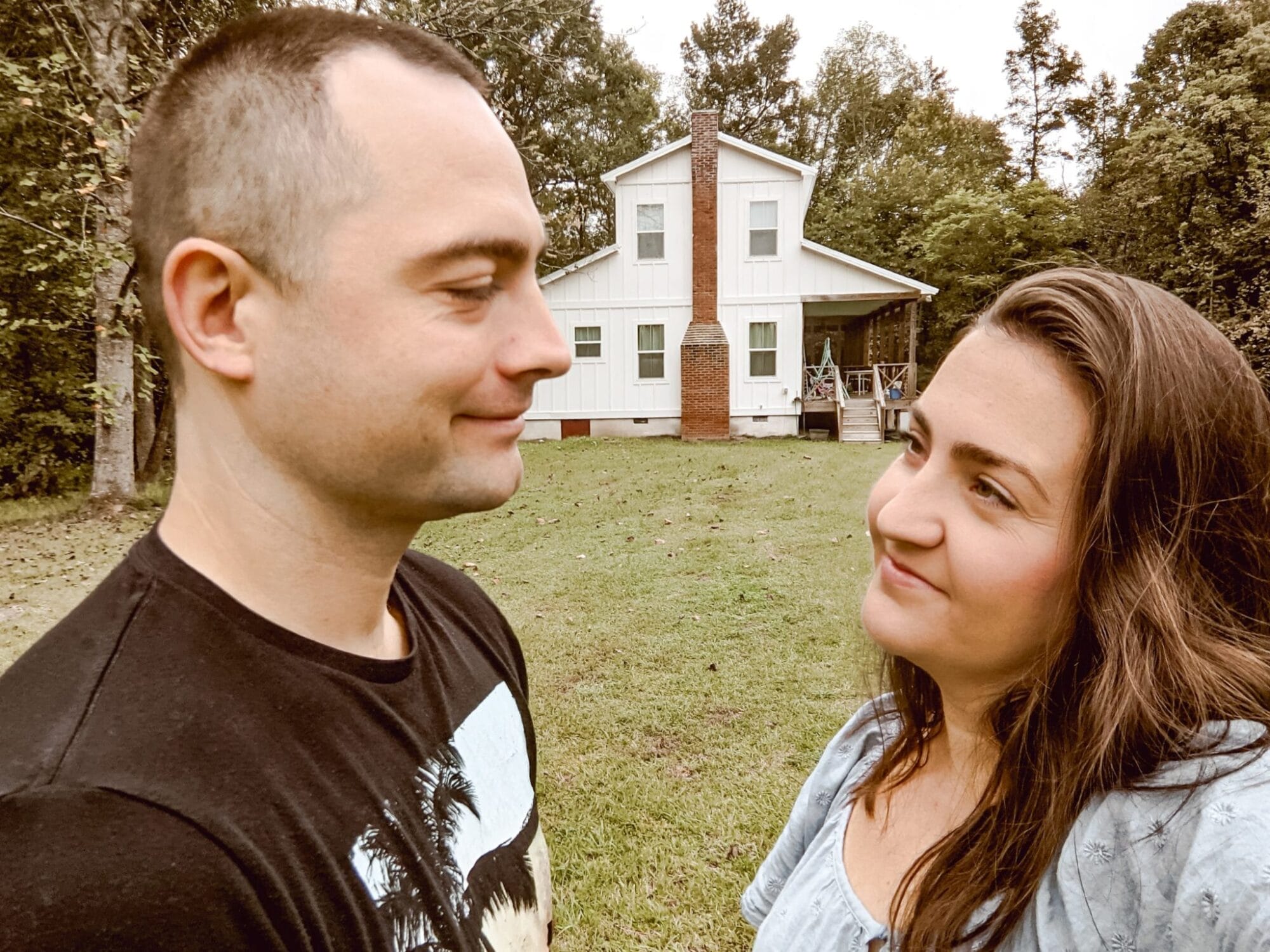 couple in front of fixer upper farmhouse