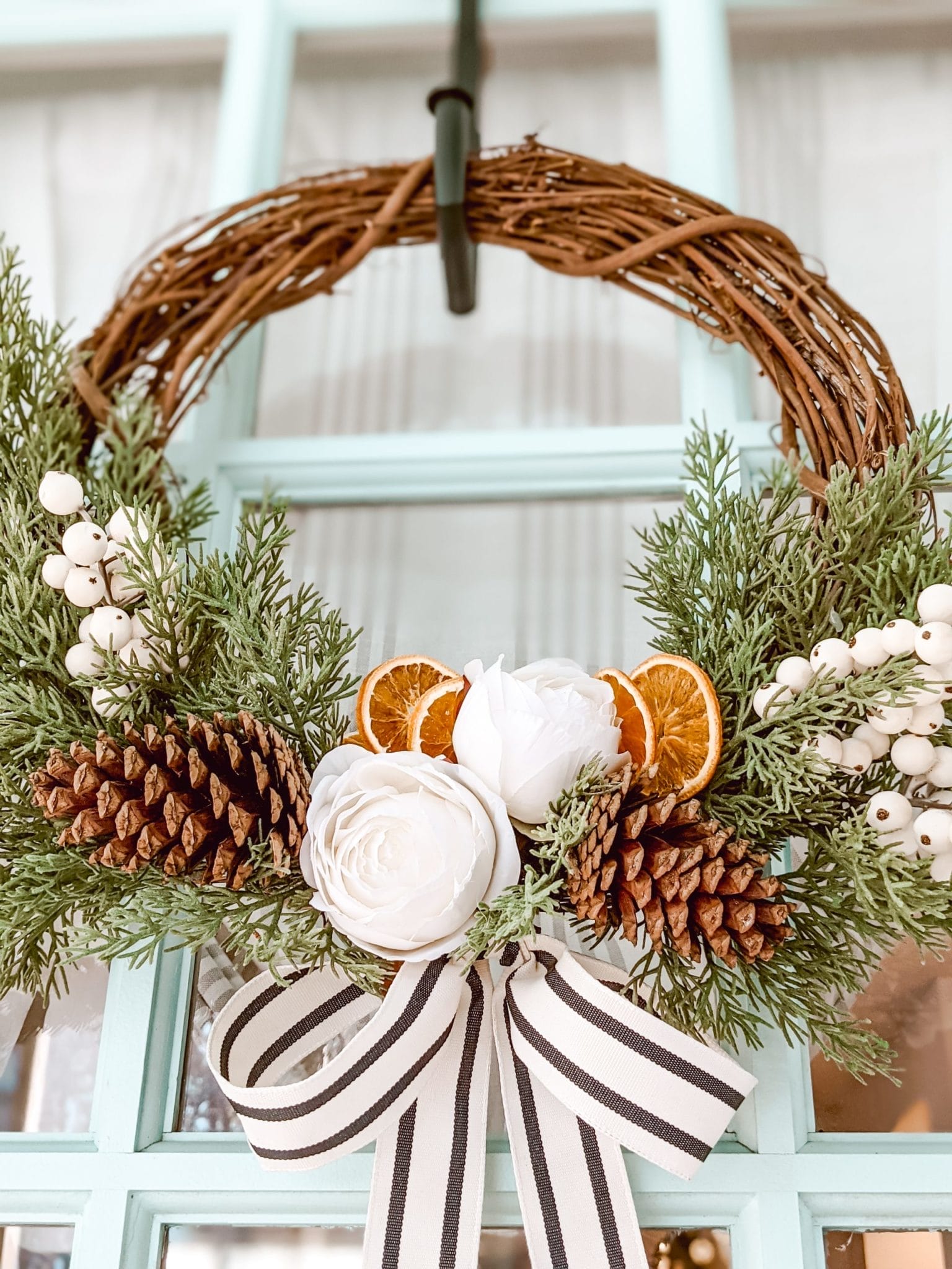 classic grapevine wreath with faux cedar, pine cones, white florals and dried oranges