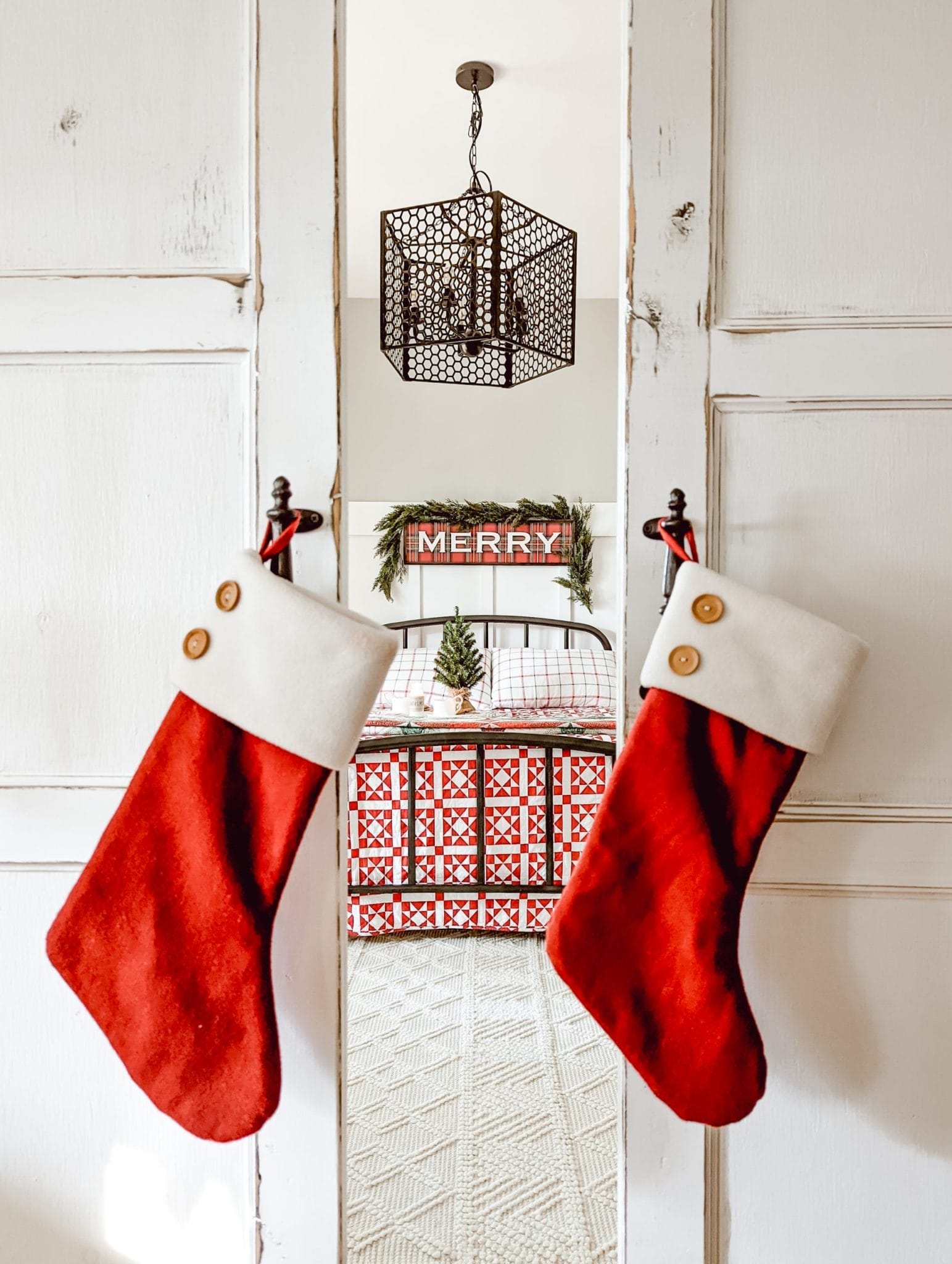 red stockings hung on sliding barn doors looking into red Christmas bedroom
