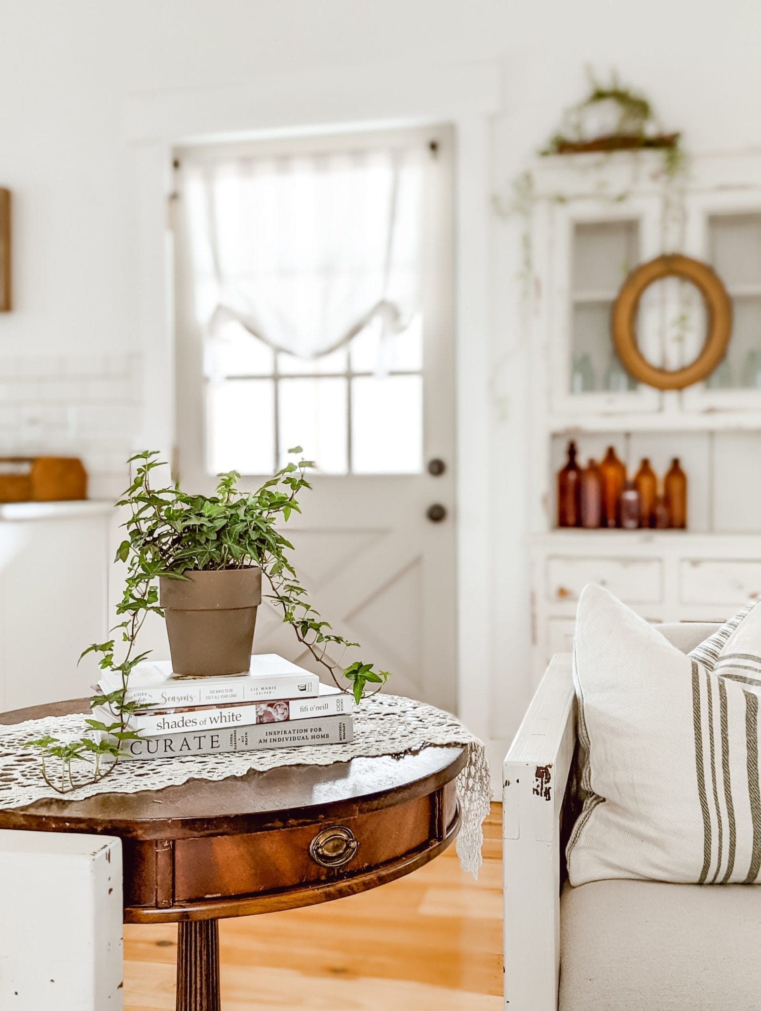 trailing ivy atop coffee table books on vintage drum table