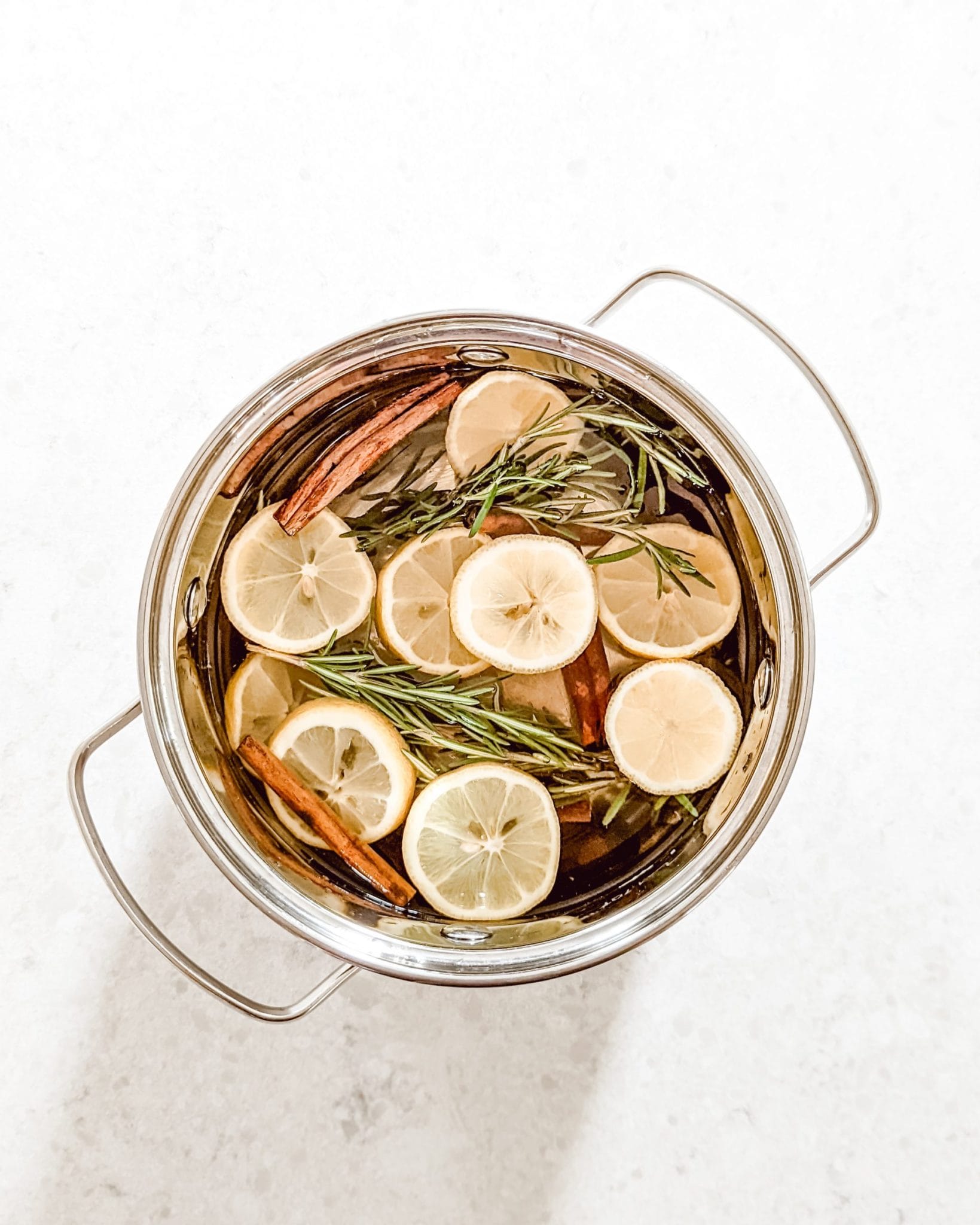 fresh smelling spring simmer pot recipe with sliced lemons, sprigs of rosemary, cinnamon sticks, and vanilla extract