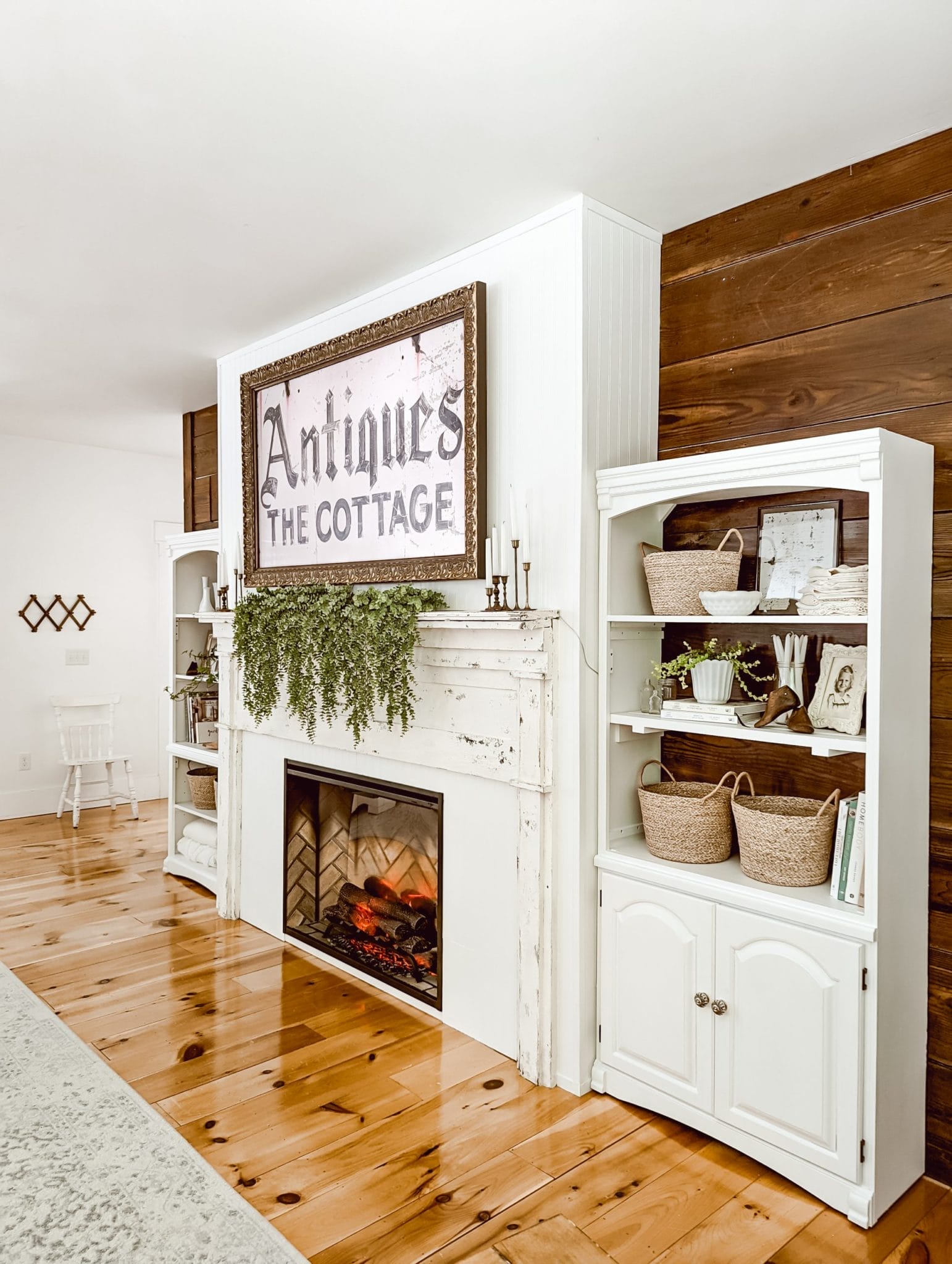 DIY farmhouse fireplace with an antique mantel, built-in shelves, a frame TV above the fireplace, and an electric fireplace insert styled in whites and wood tones