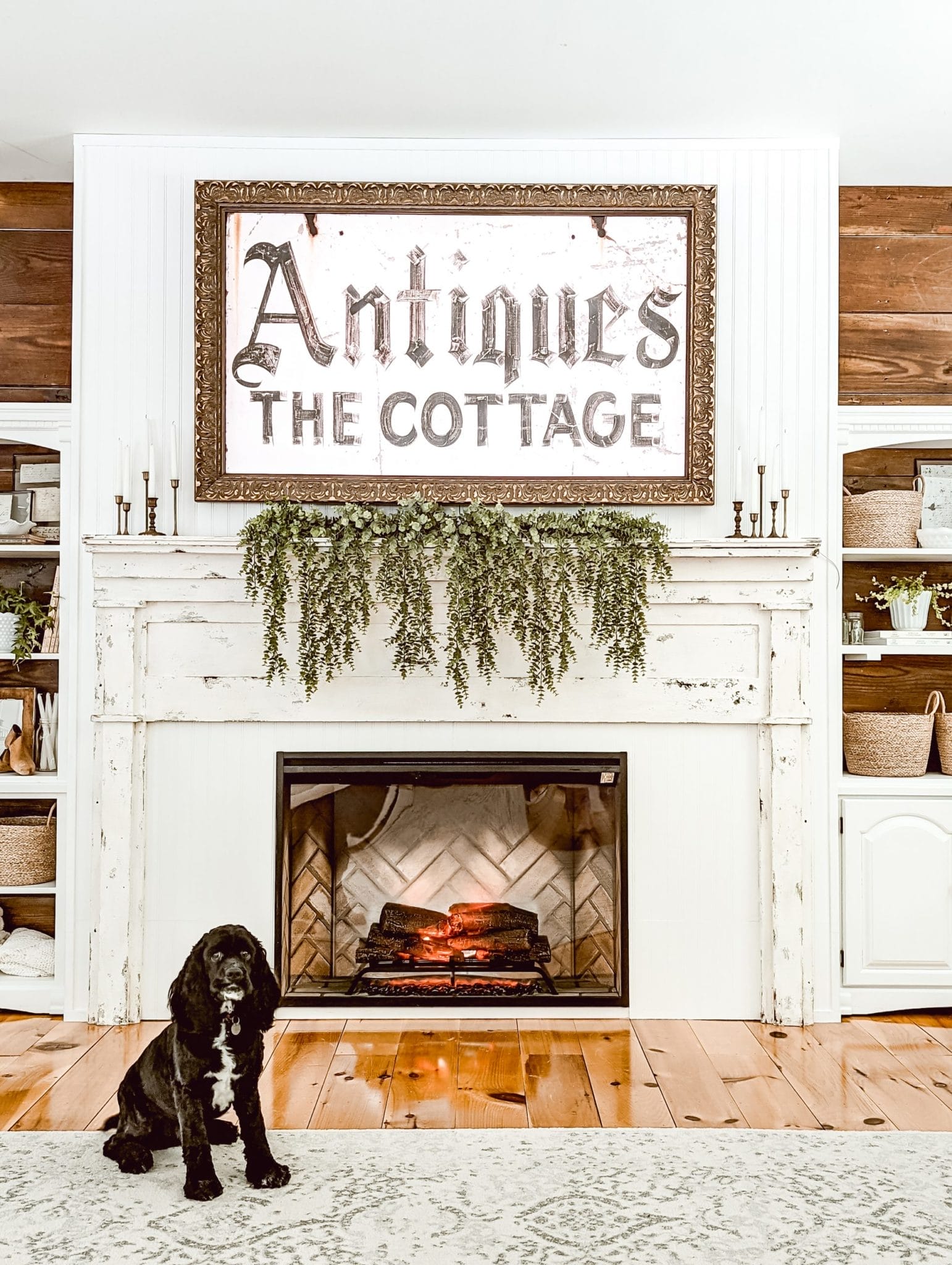 Cocker Spaniel in front of DIY farmhouse fireplace with an antique mantel, a frame TV above the fireplace, and an electric fireplace insert