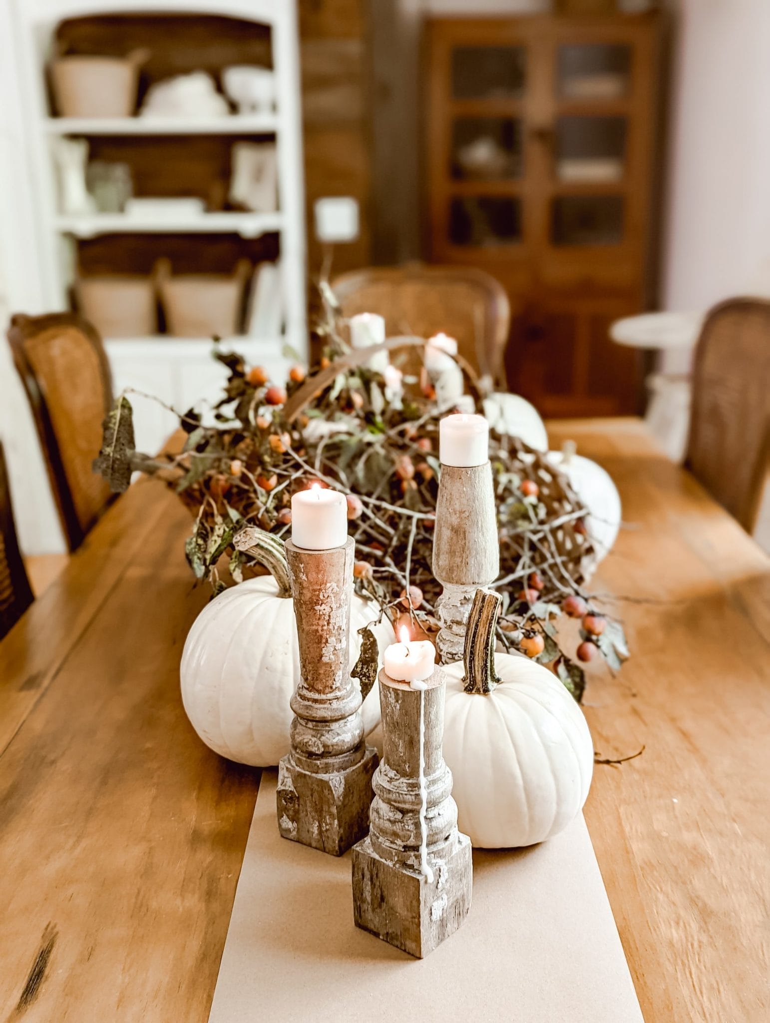 thanksgiving table with white pumpkins, perimmons, and chippy white candlesticks