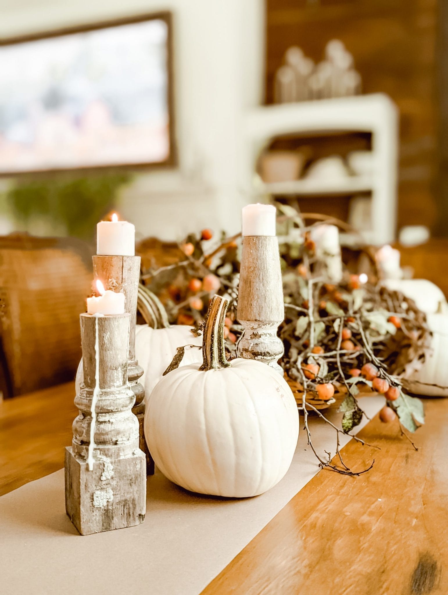 thanksgiving table with white pumpkins, perimmons, and chippy white candlesticks