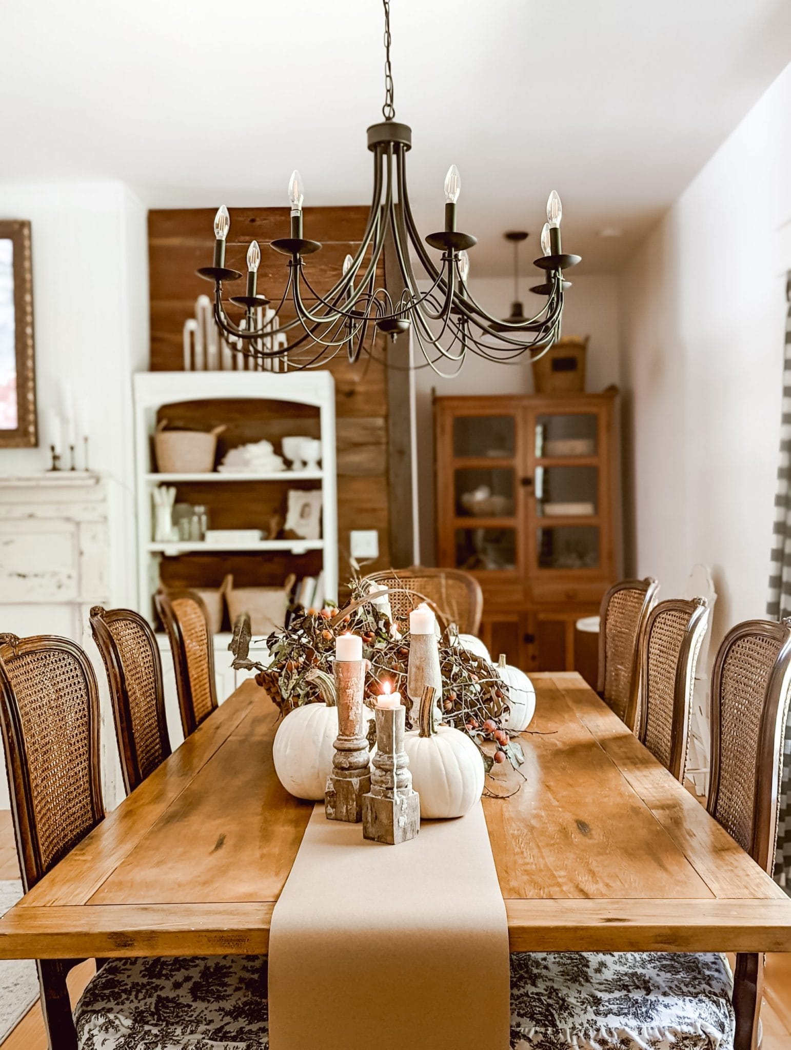 farmhouse table decor for fall using pumpkins, candles, and persimmons