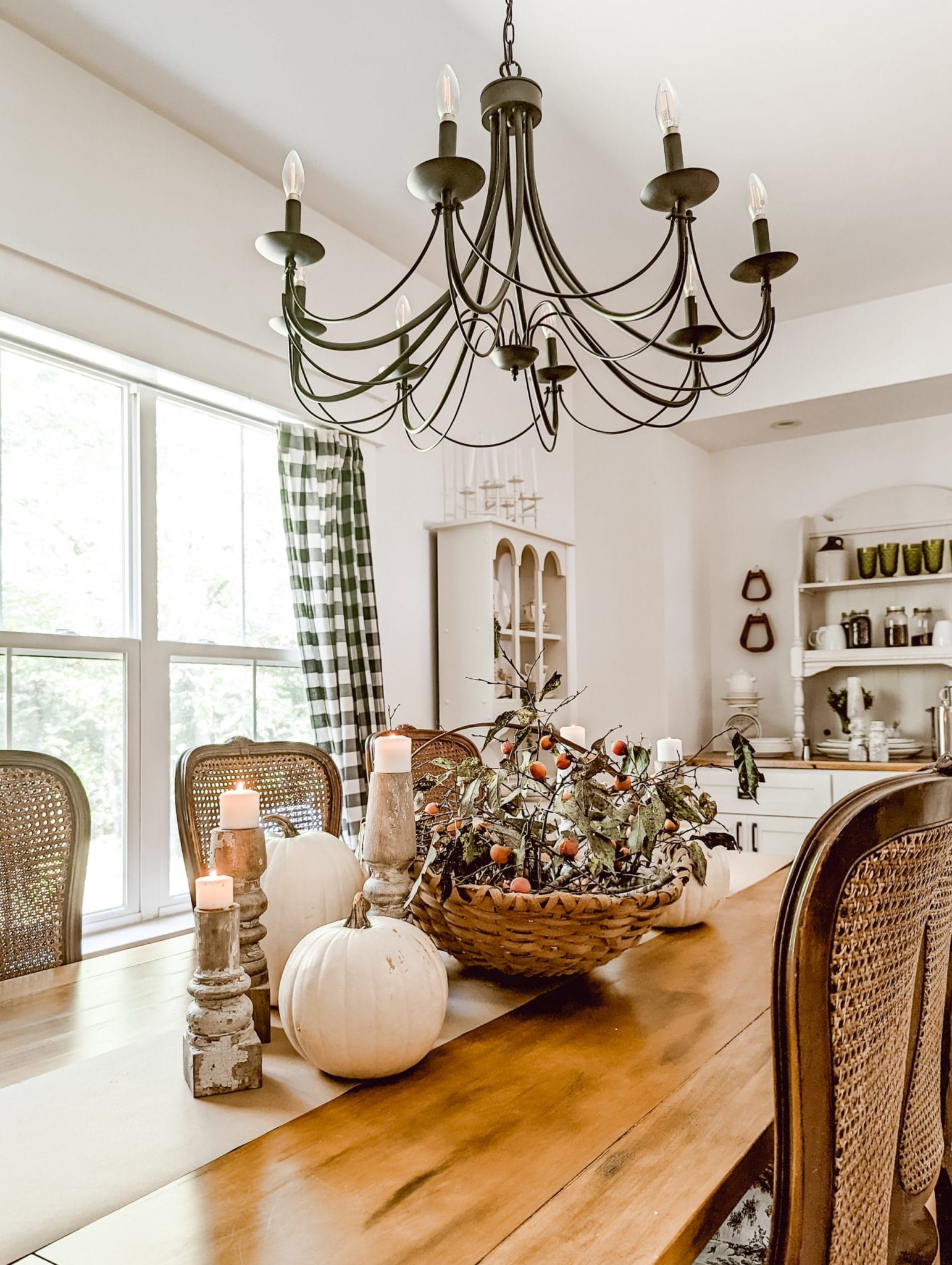 thanksgiving table with white pumpkins, harvest basket foll of perimmon branches, and chippy white candlesticks