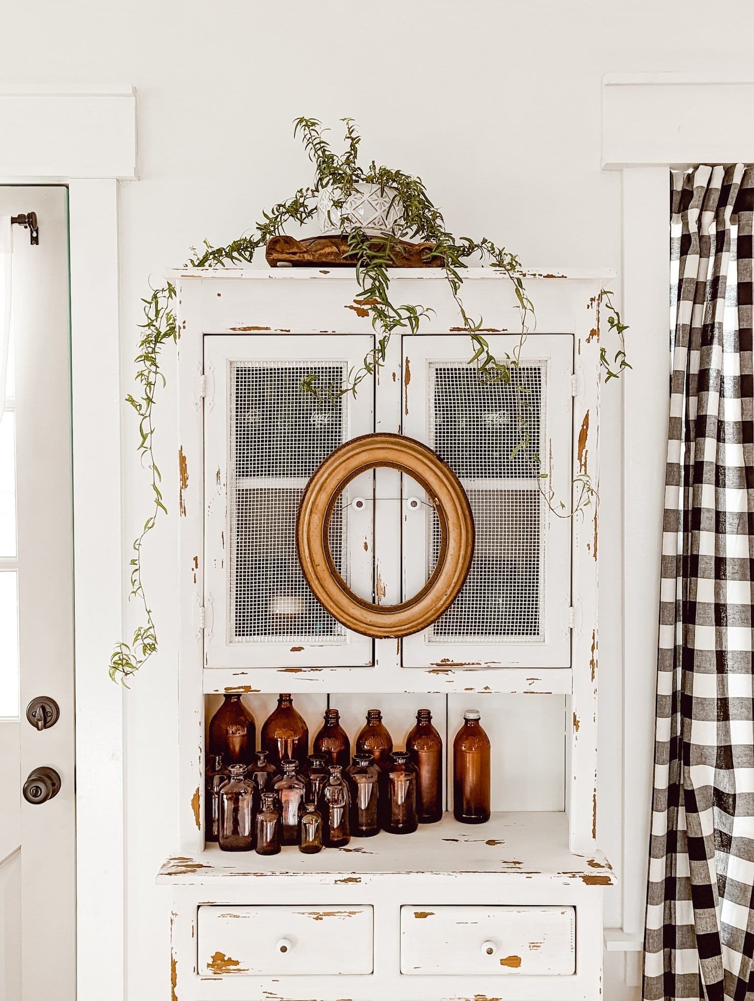 collection of vintage and antique amber glass bottles on a chippy white farmhouse cabinet