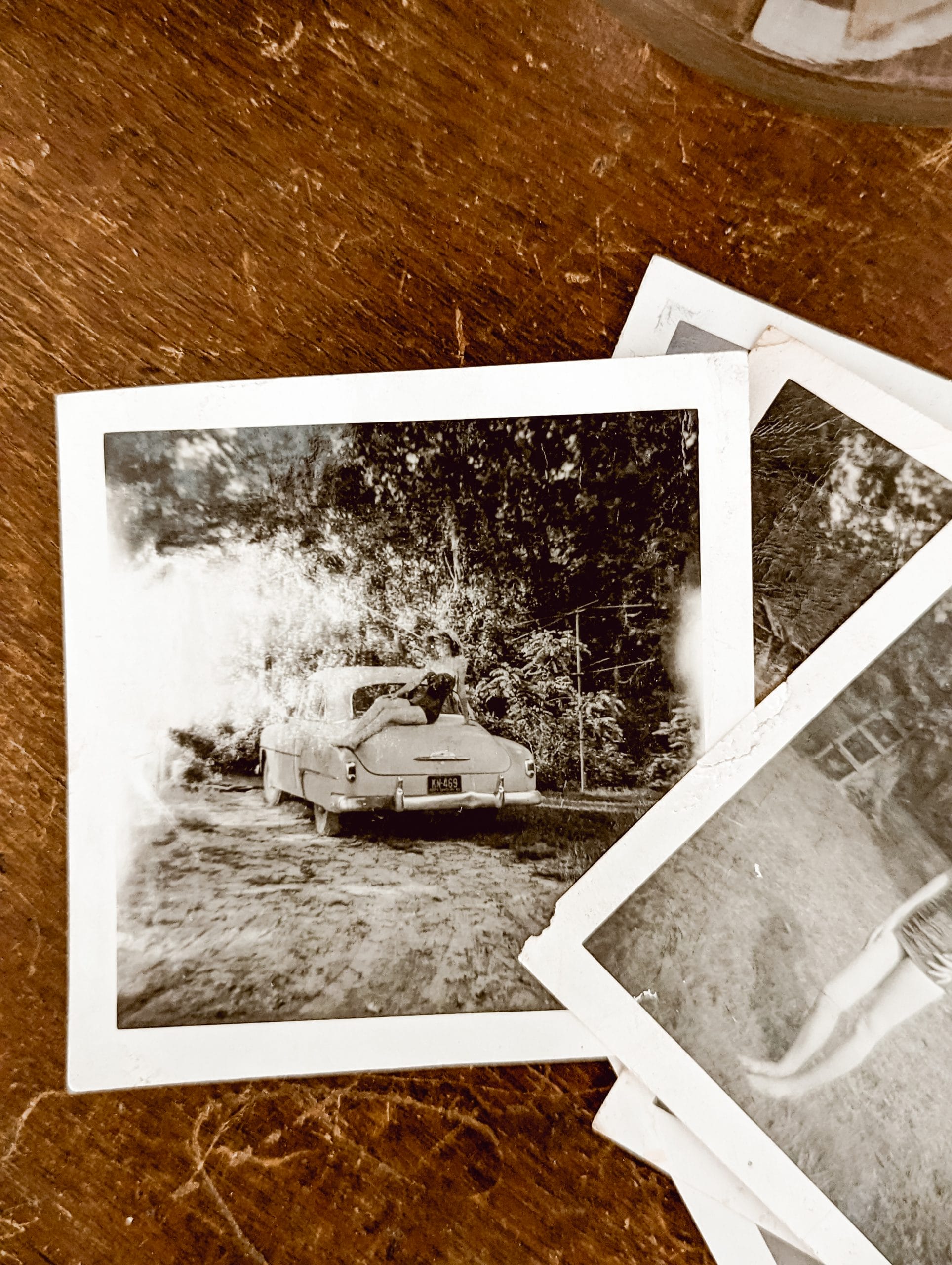 black and white photo from the 1950's of a girl in a bathing suit sitting on an old car