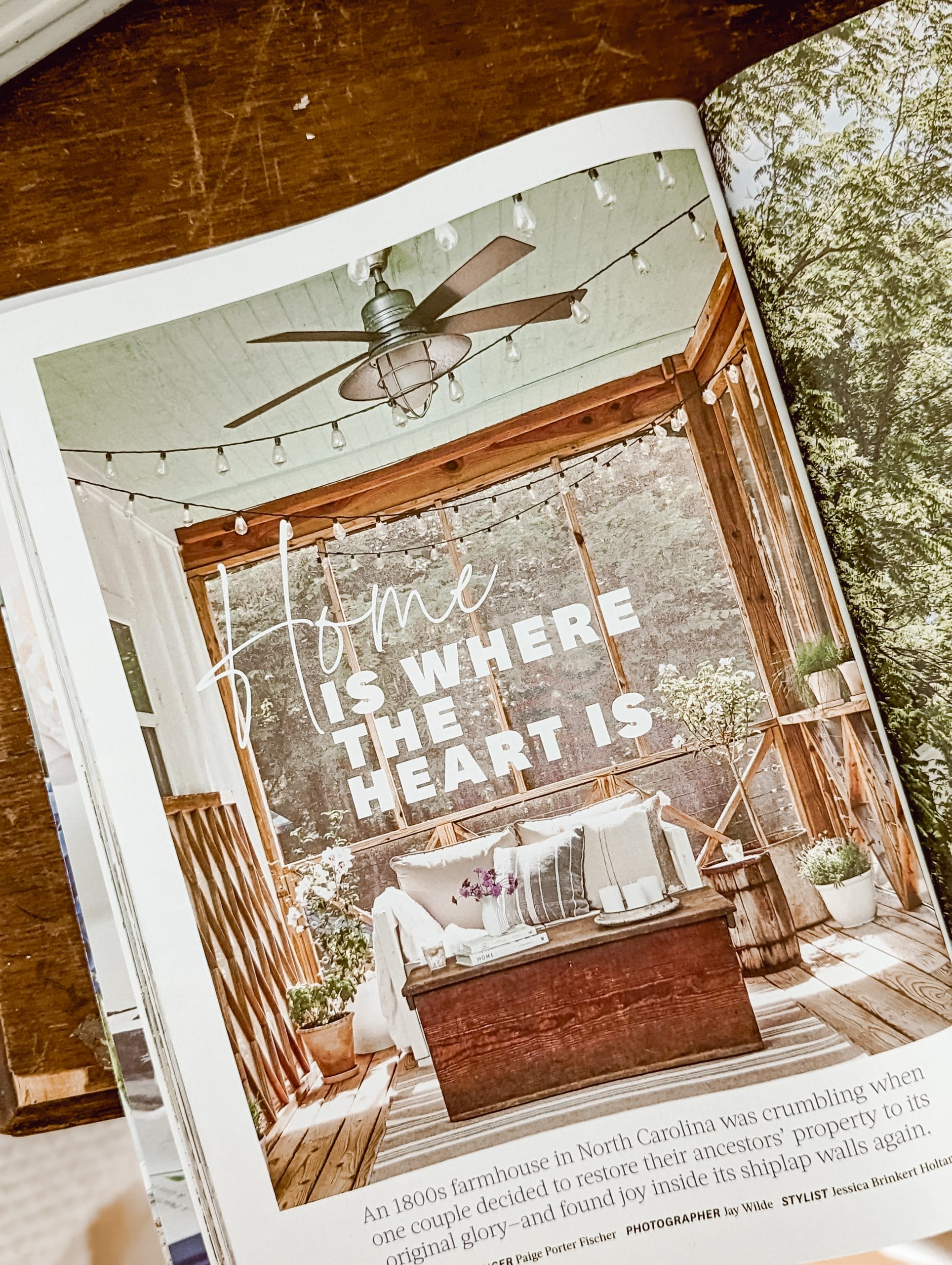 Farmhouse screened in porch with haint blue ceilings, string lights, and a galvanized ceiling fan, and an old wooden trunk coffee table