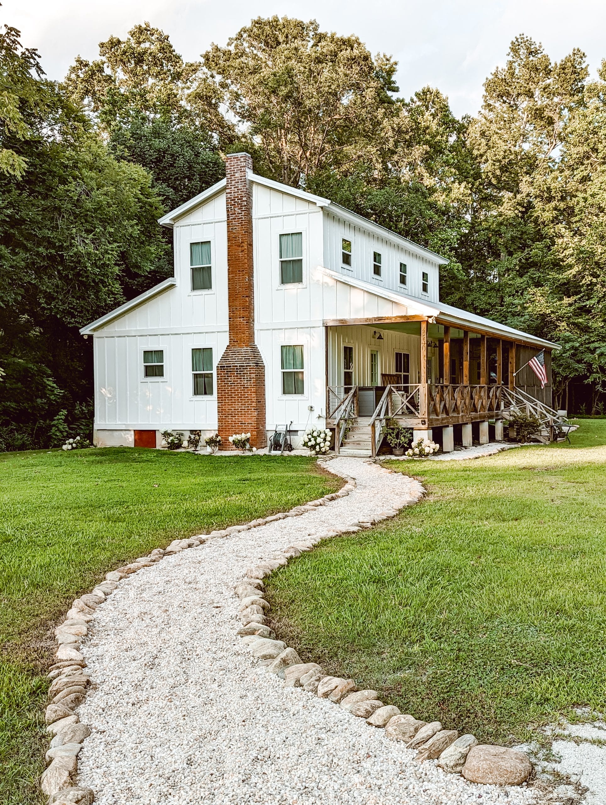 cottage style pea gravel garden path leading the way to a white farmhouse in the woods