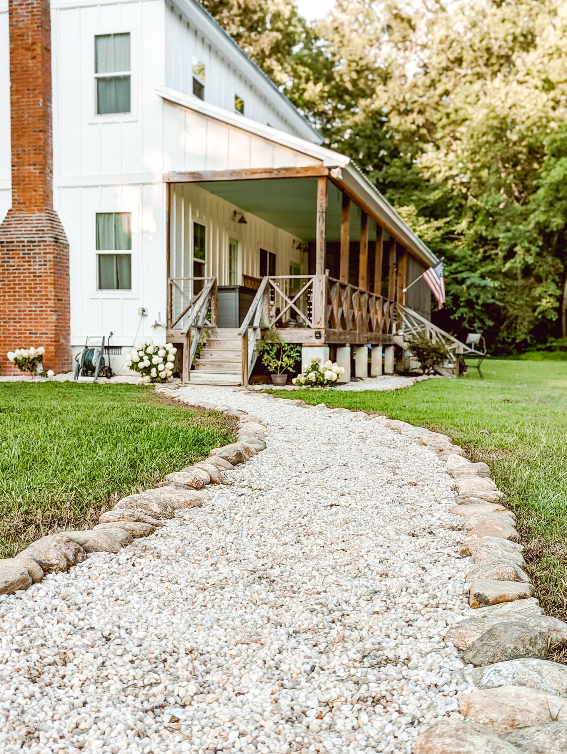 a cottage garden path lined with natural stone border and filled with white pea pebbles