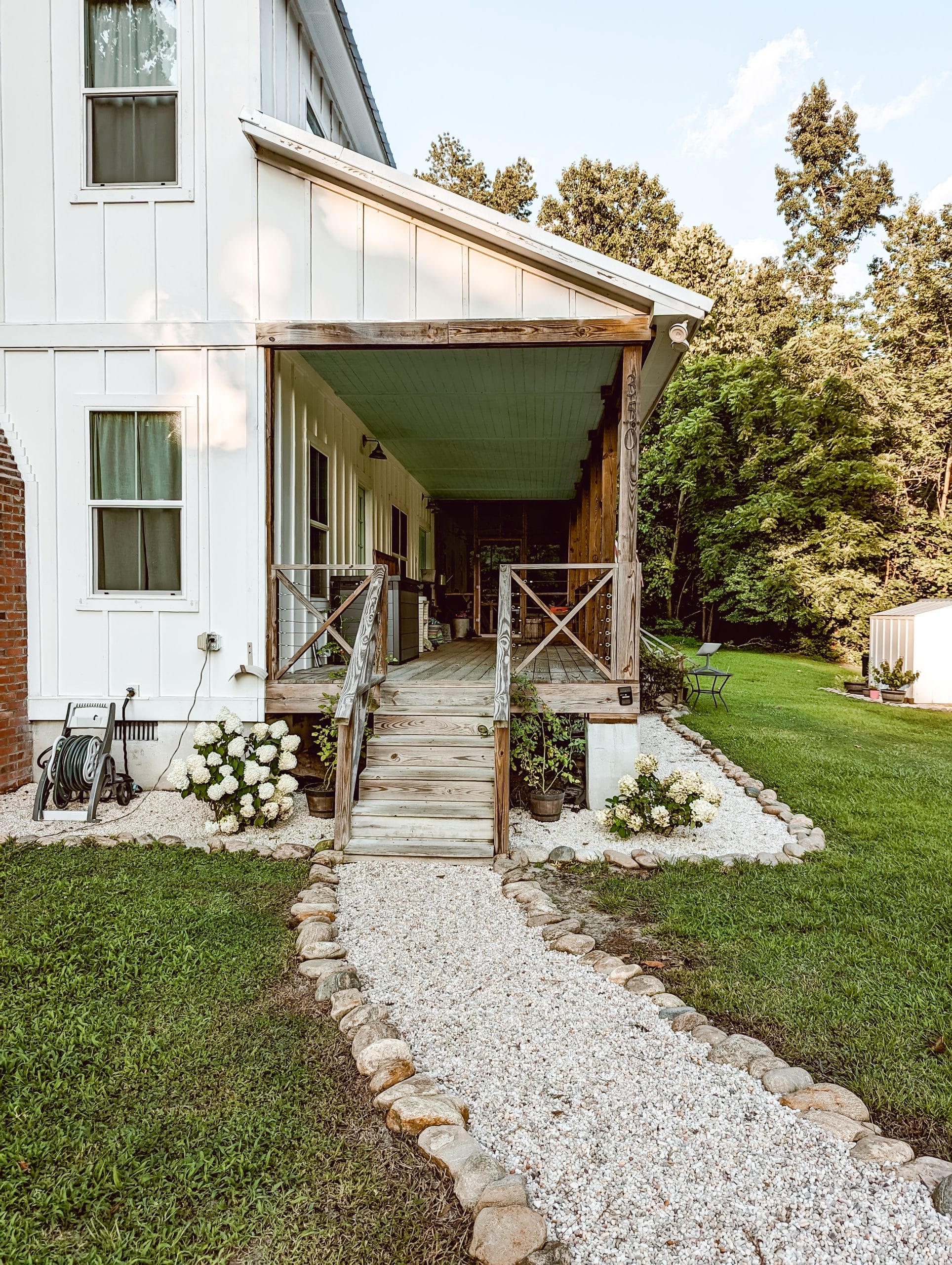 country farmhouse front porch steps leading to a gravel walkway
