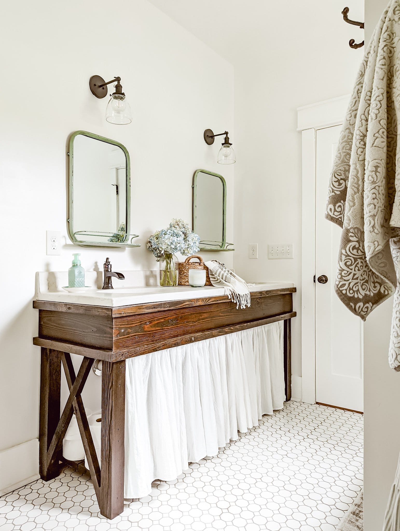 farmhouse bathroom vanity from reclaimed wood with a white cabinet skirt and fresh blue hydrangeas on the counter