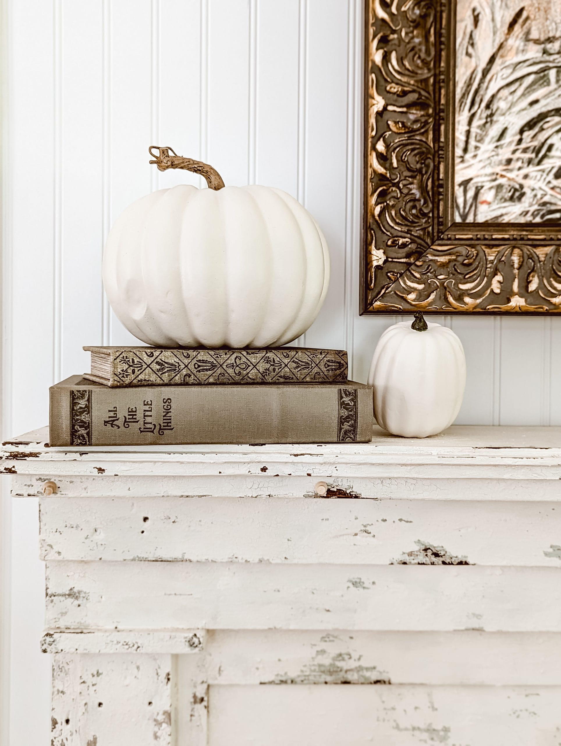 white pumpkins stacked on top of two vintage style green book boxes