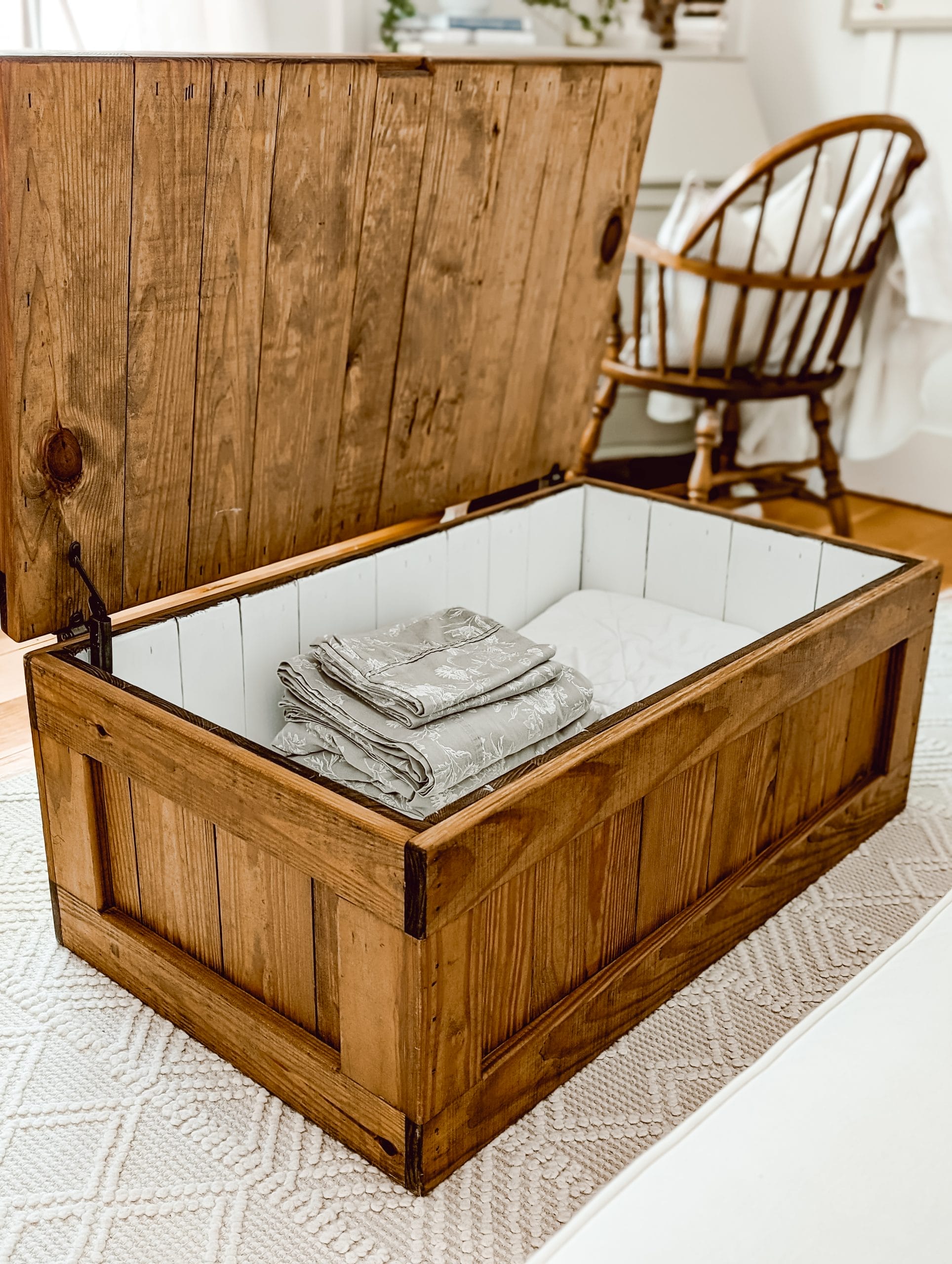 vintage pine wood chest with the inside painted white to serve as extra linen storage in a guest bedroom