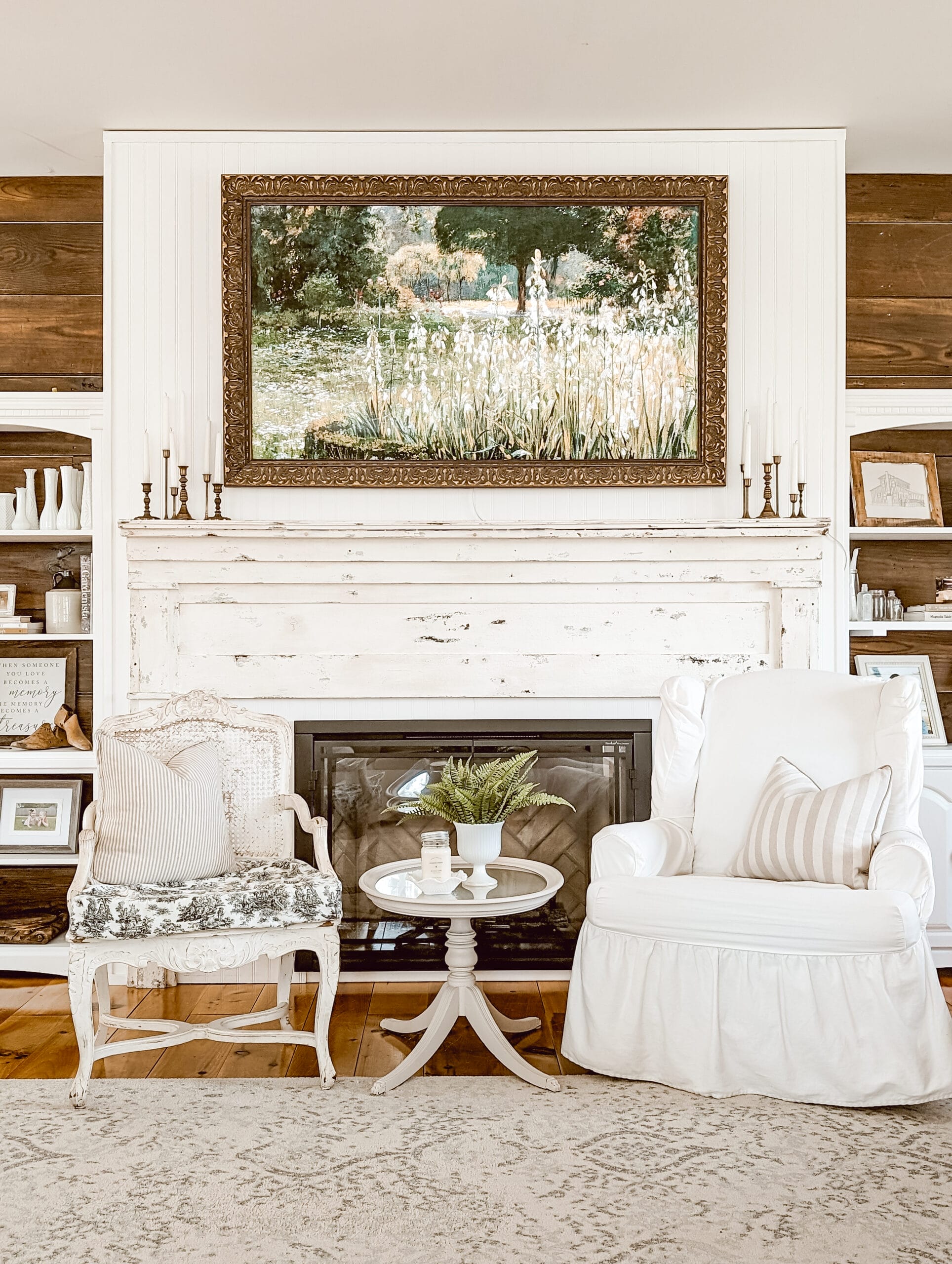 frame tv with a gold frame and spring floral tv art over an antique mantel in a white cottage farmhouse living room