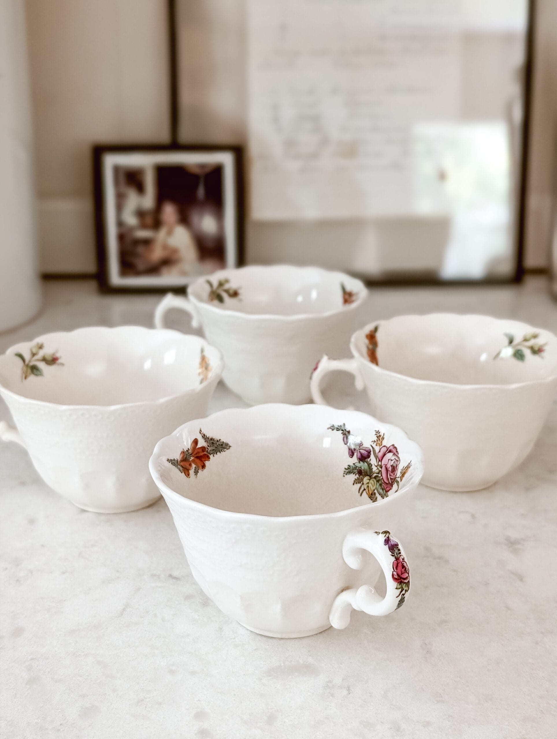 4 white antique teacups with a floral pattern on the handle and inside the cup