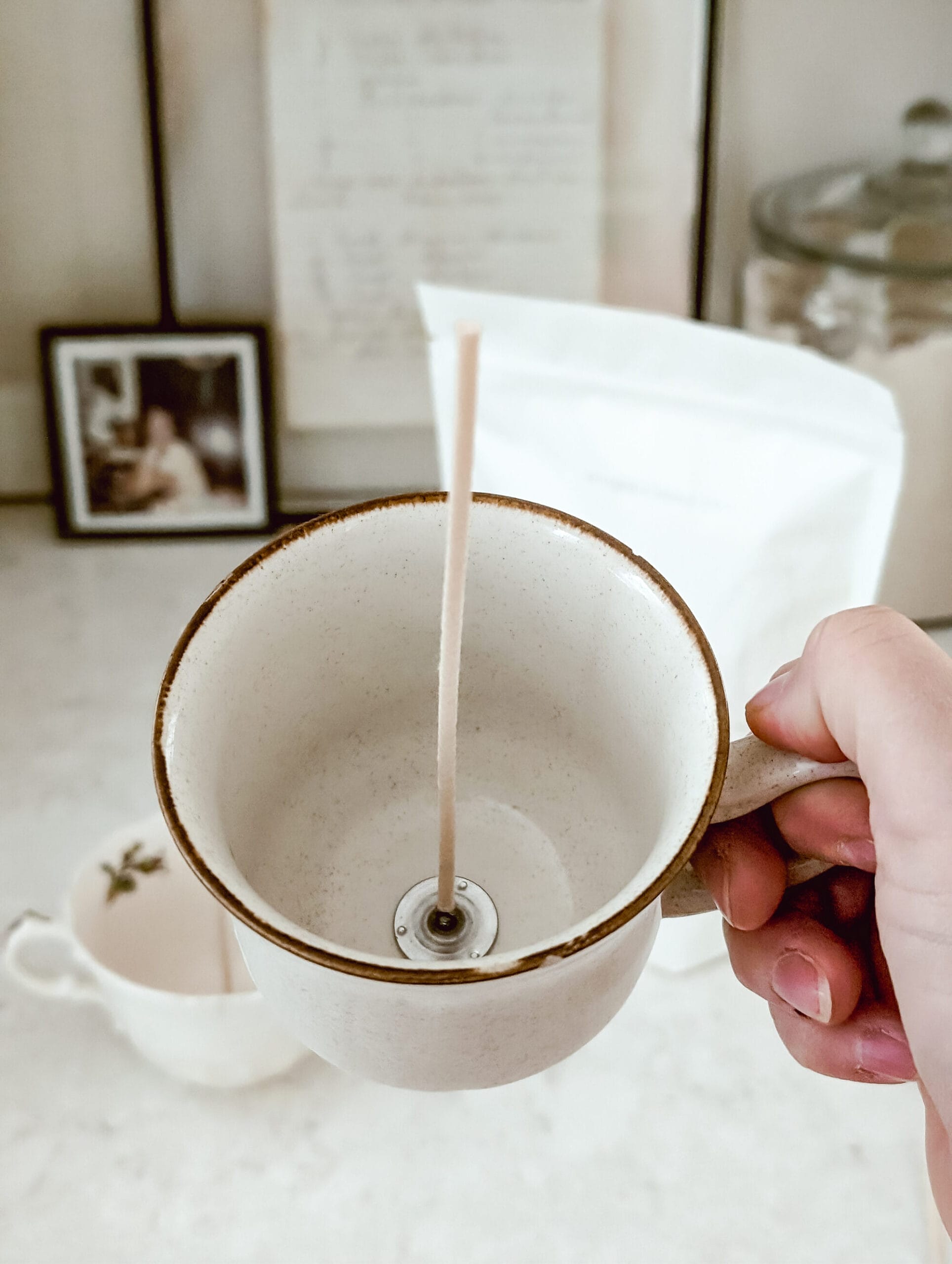 attaching a cotton candle wick to a vintage teacup to make a DIY candle