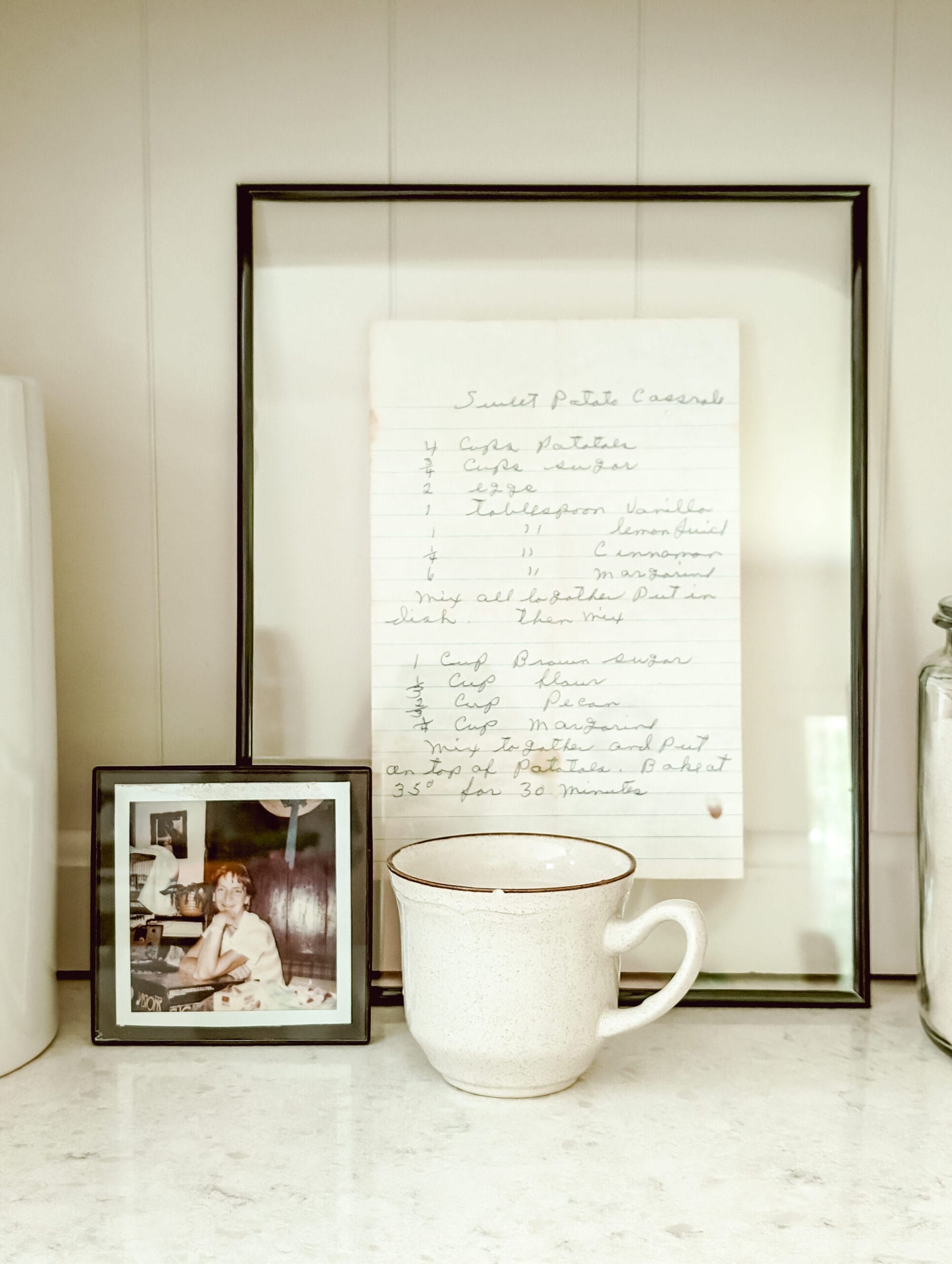 DIY vintage teacup candle next to a photo of a Grandmother and a framed handwritten recipe