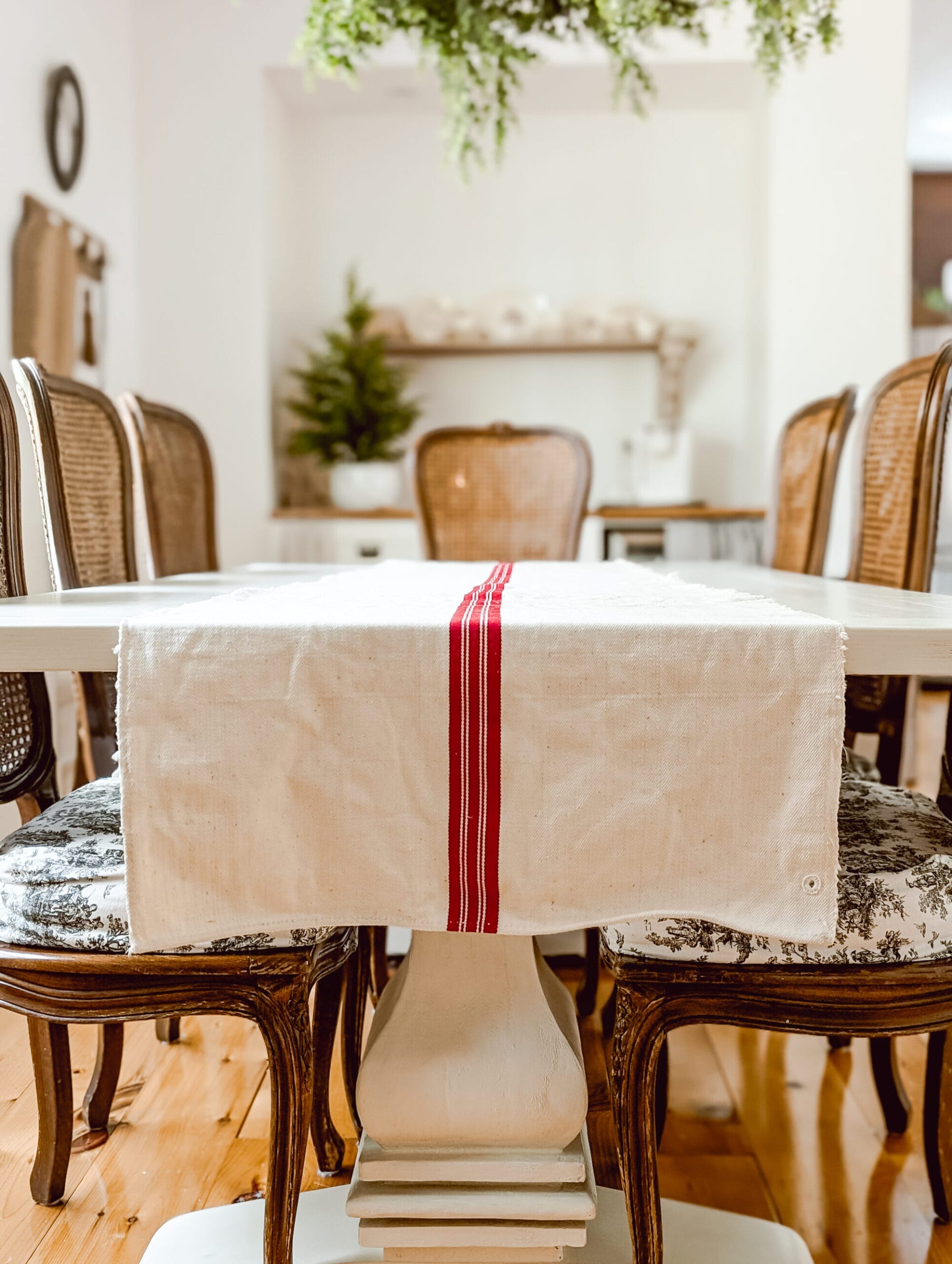 antique grain sack table runner on a white painted farmhouse trestle table with vintage french caned wood chairs