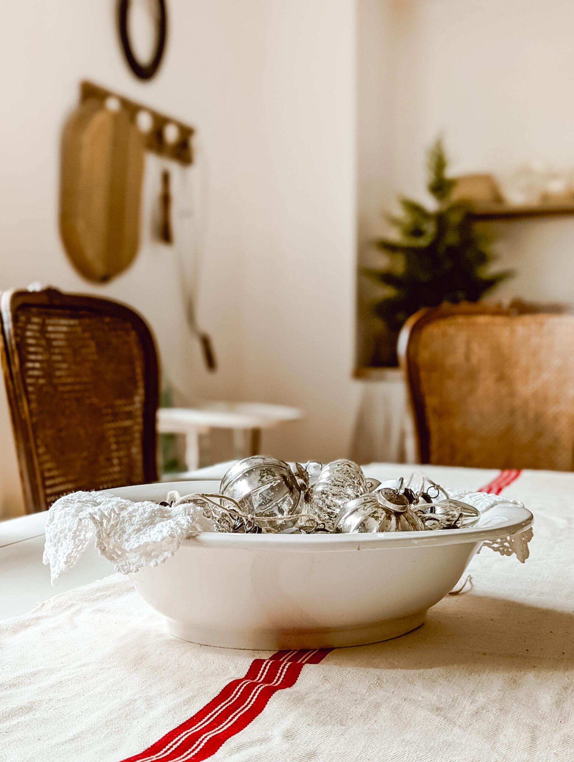 antique white bowl filled with a collection of mercury glass Christmas ornaments