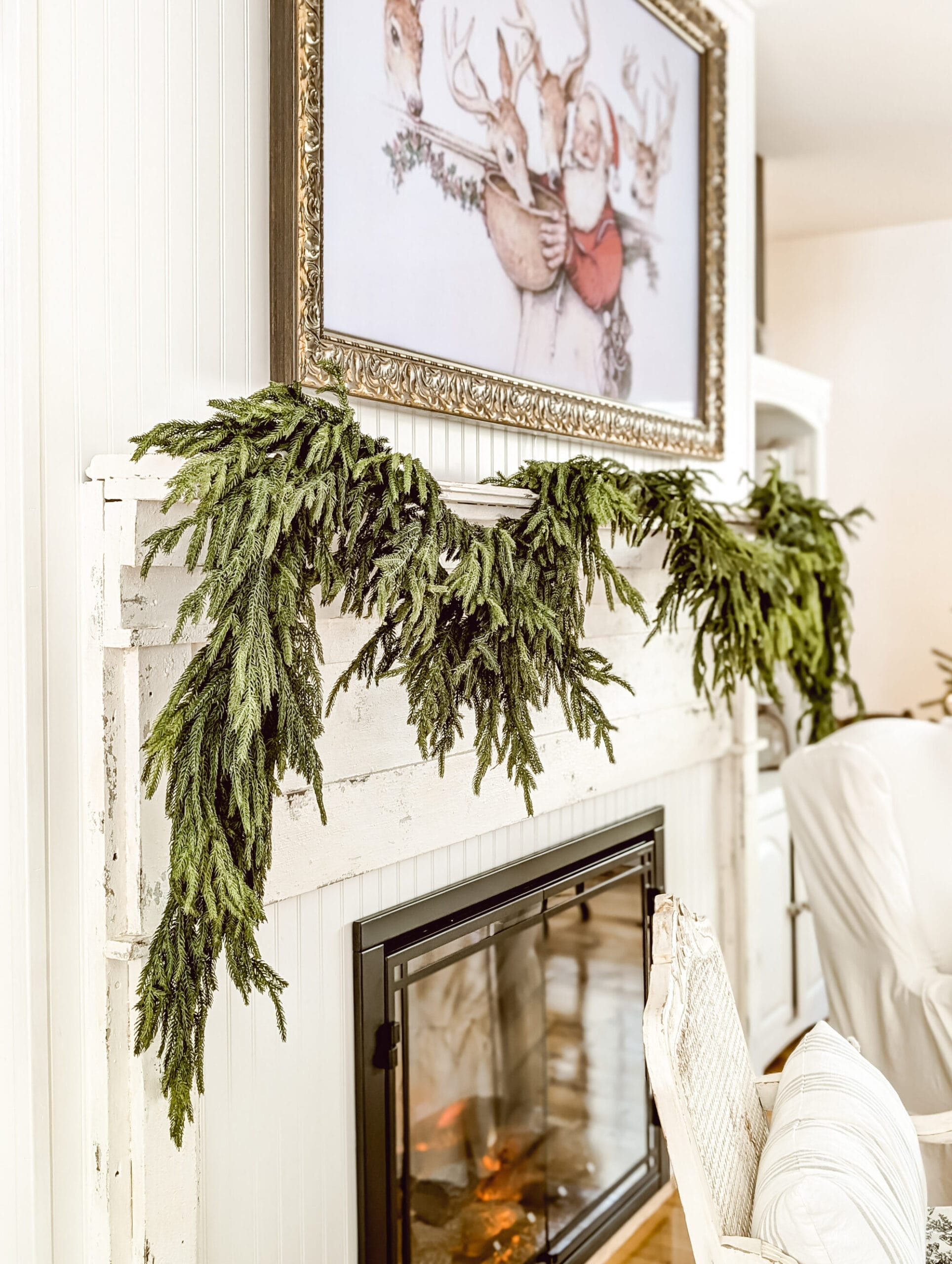 norfolk pine garlands layered on a long chippy white farmhouse fireplace mantel