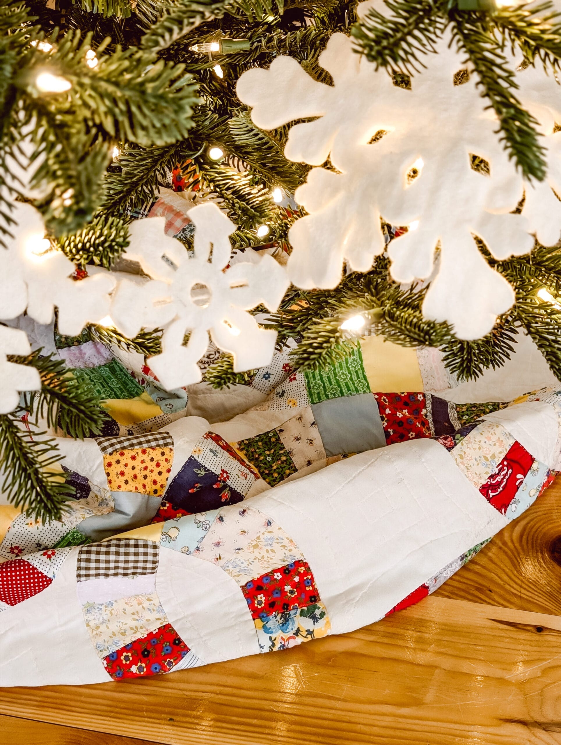 white felt snowflake garland on a Christmas tree with an antique quilt tree skirt