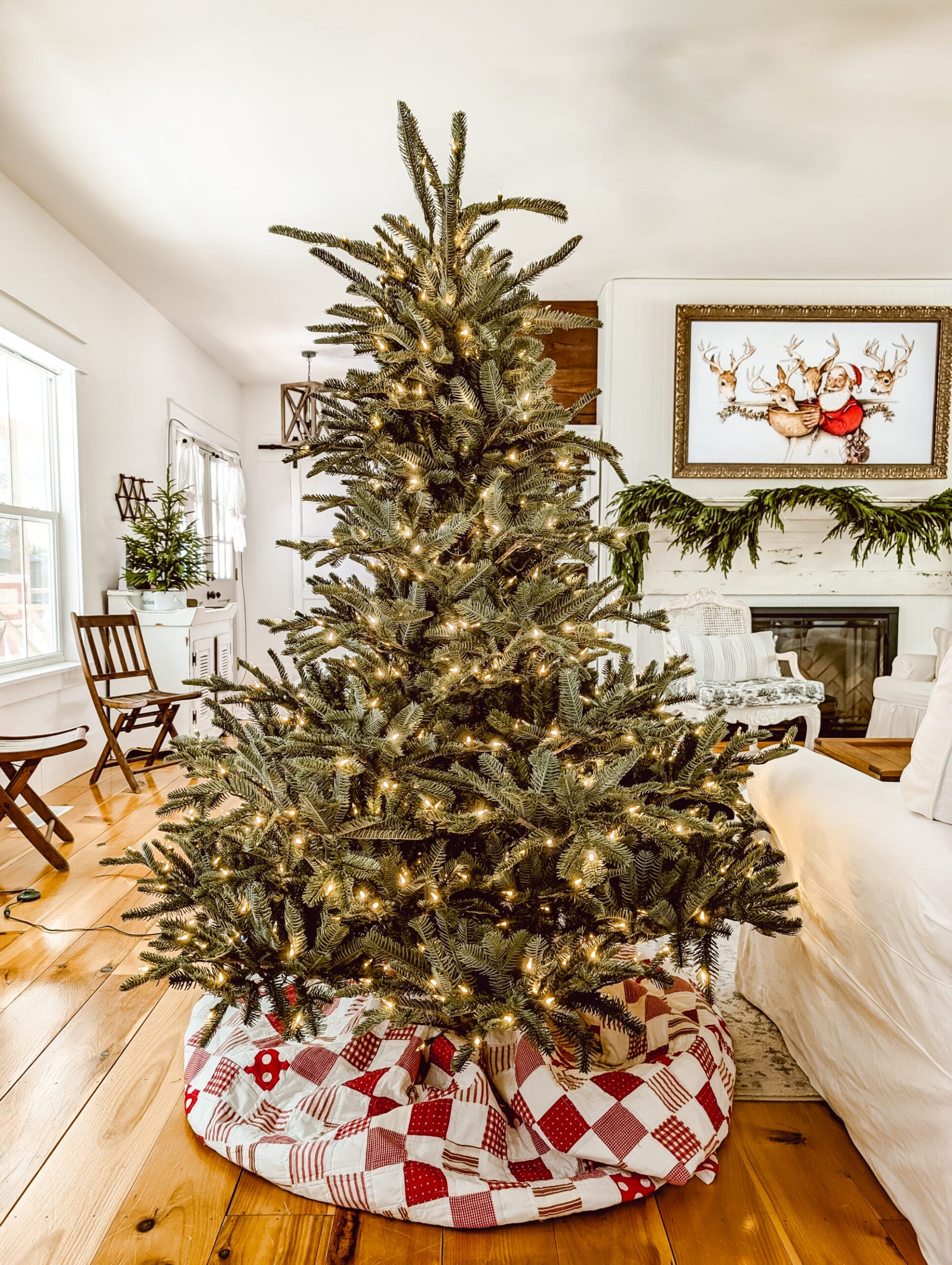 real life look at Balsam Hill's European Fir tree fluffed but not yet decorated, and with a red and white quilt as a tree skirt and white lights