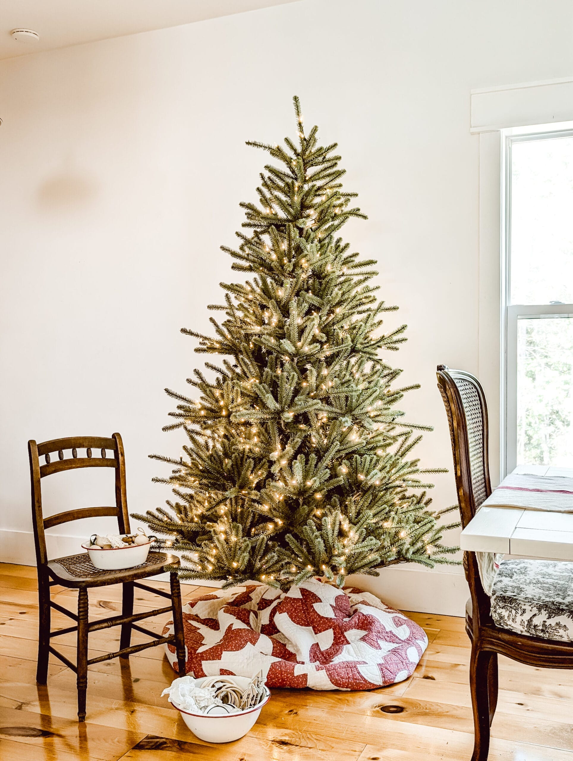 real life look at Balsam Hill's Sanibel Spruce fluffed but not yet decorated, and with an antique quilt as a tree skirt and white lights